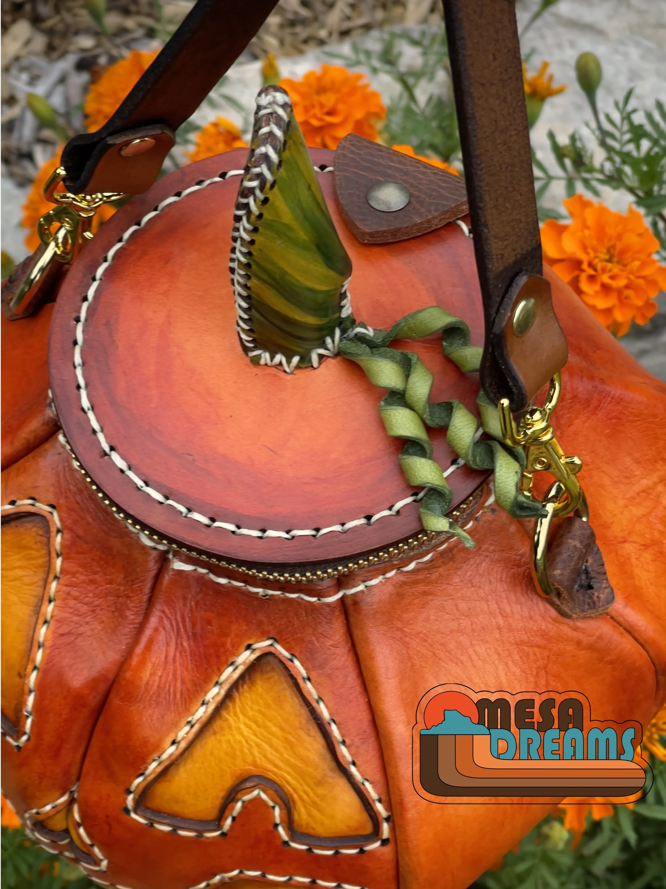 a top view of the pumpkin bag highlighting the stem on the lid as well as the spiraled green tendrils that are sewn onto the lid. The stem is handpainted in greens and yellows.