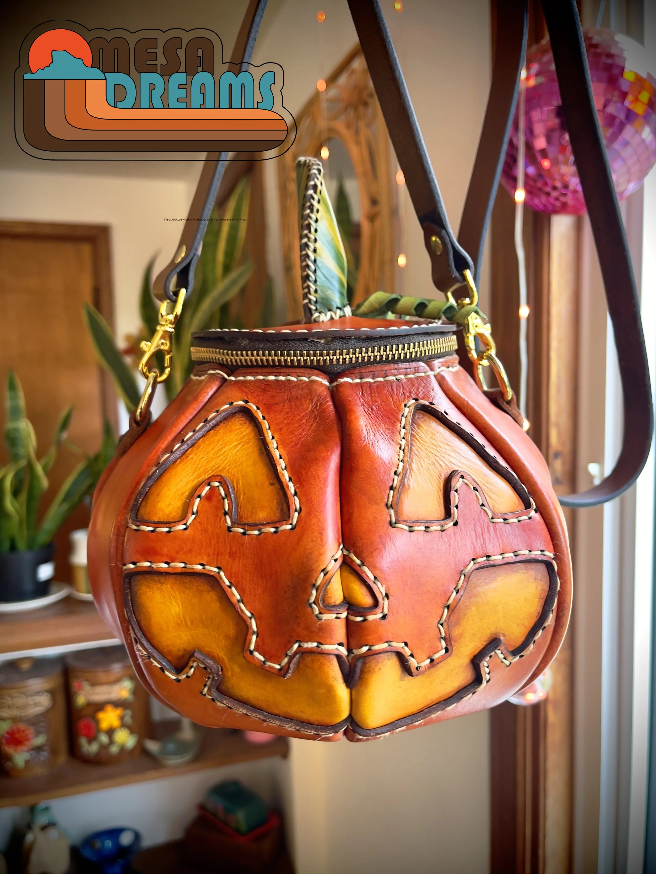 The Great Pumpkin bag hanging in my home stfudio in front of green snake plants and twinkle lights.