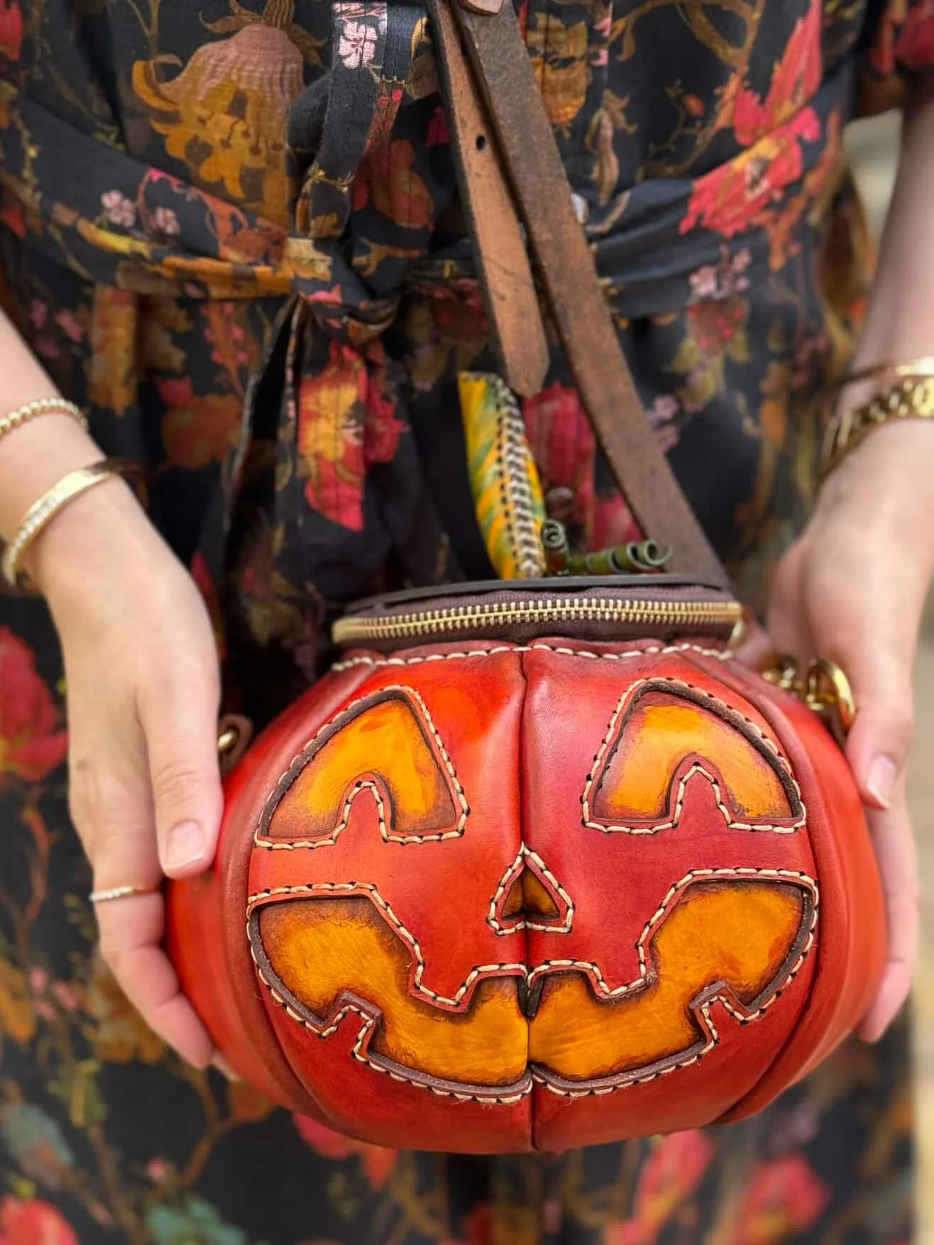 A Great Pumpkin leather bag being held against a beautiful dress covered in autumn colors and patterns