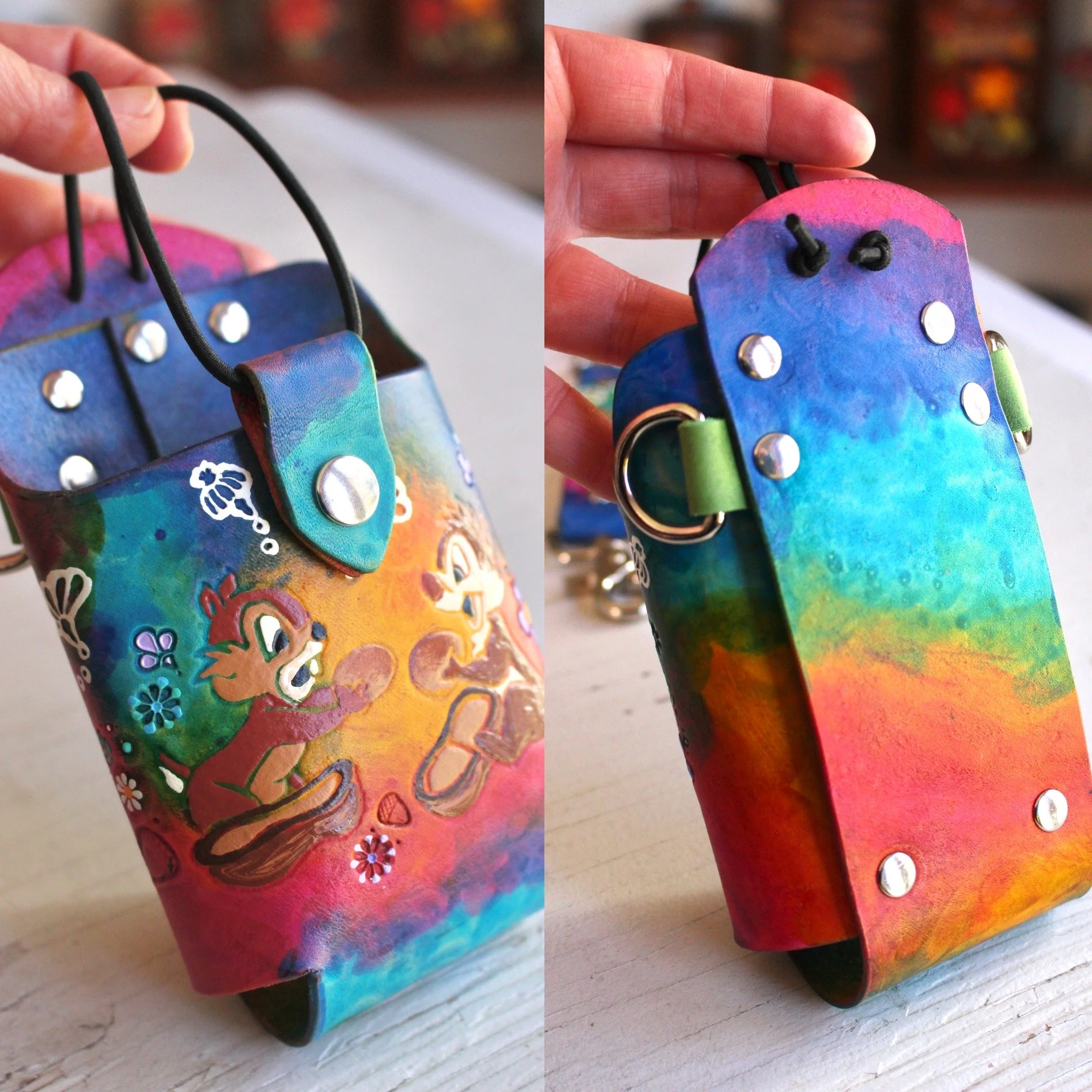 a colorful radio bucket for fire radio straps that is stained in a watercolor look with blues, pinks, yellow and teals. Cute cartoon characters are tooled into the leather