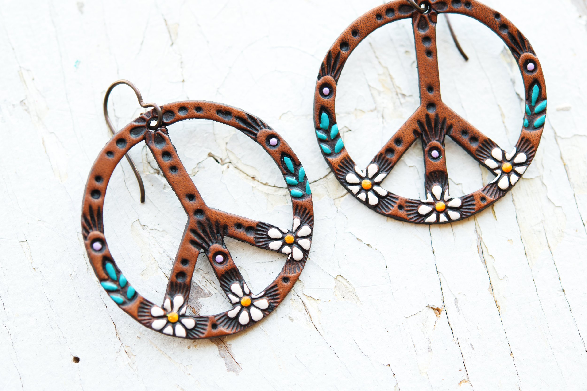 this photo shows the classic daisy peace sign earrings on a rustic white wood background.