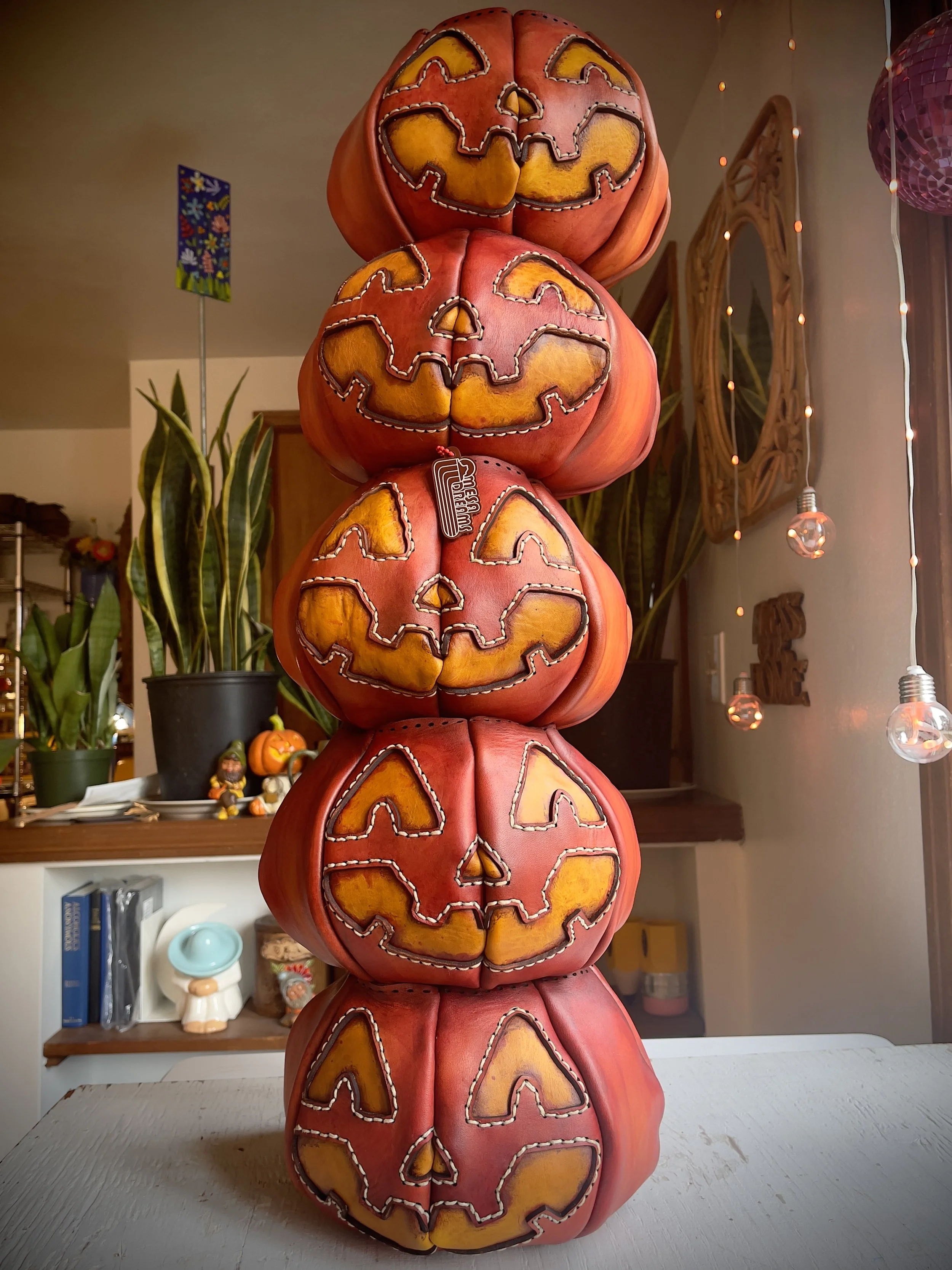 the photo shows a stack of pumpkin bag bodies in progress. 5 pumpkins are stacked one on top of another by a window.