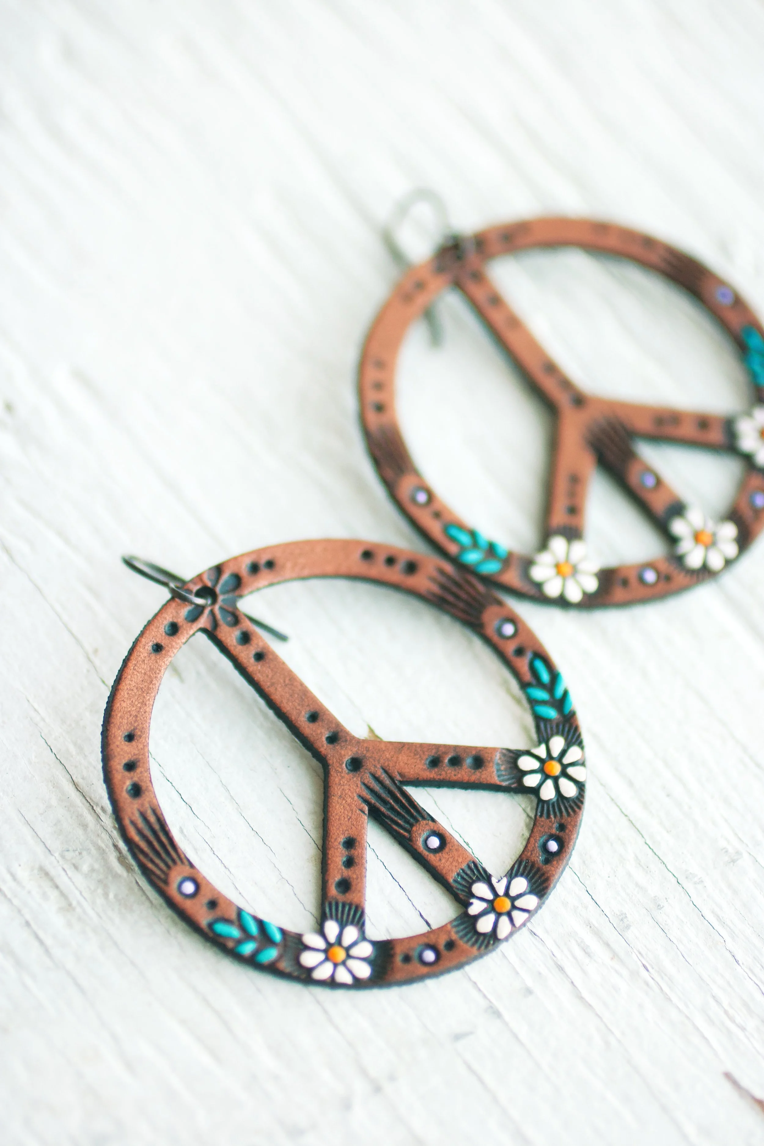 the 2” version of the classic Daisy peace sign earrings on a rustic white background