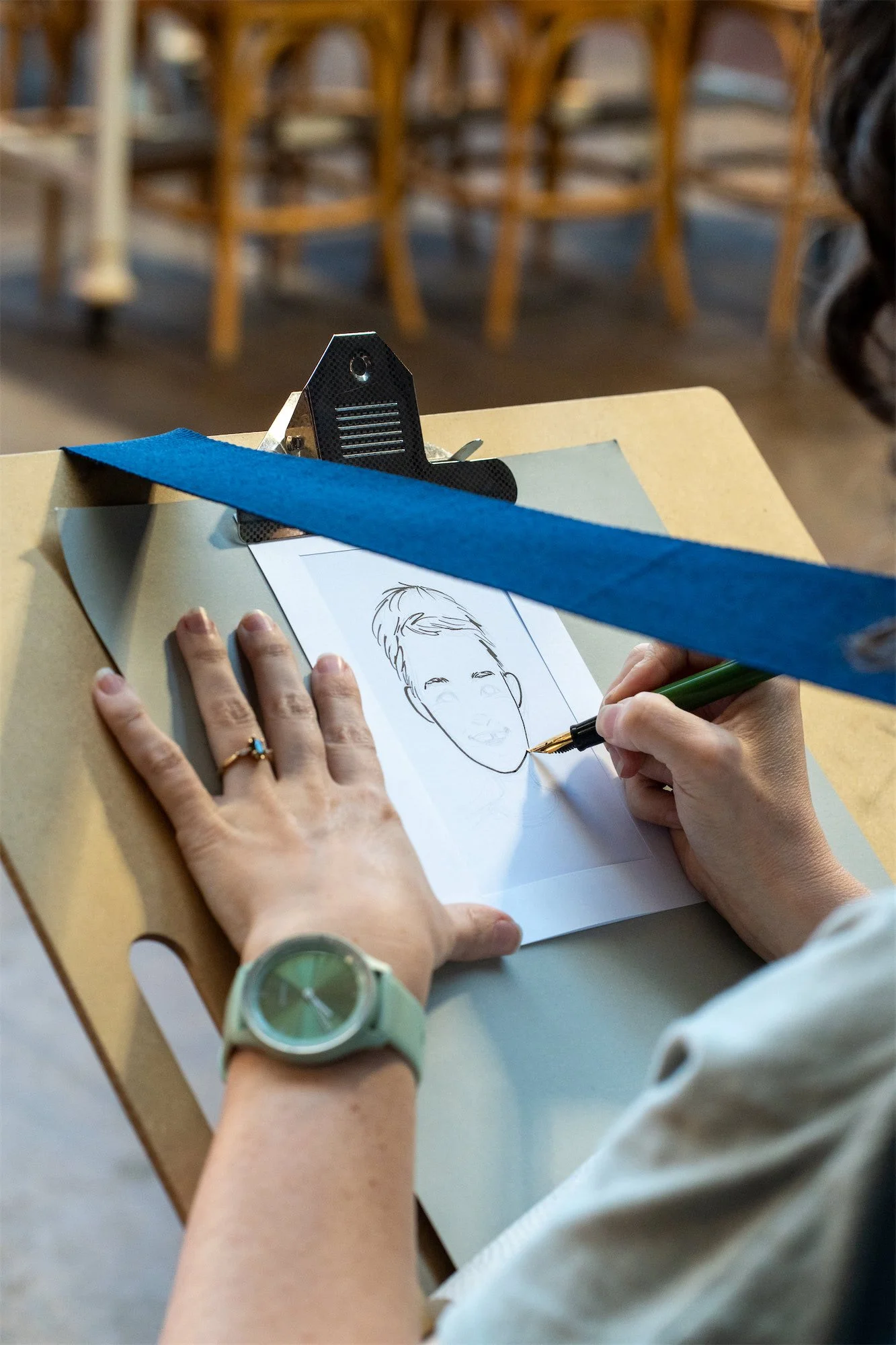 A close up of Jana drawing a boy's portrait in ink