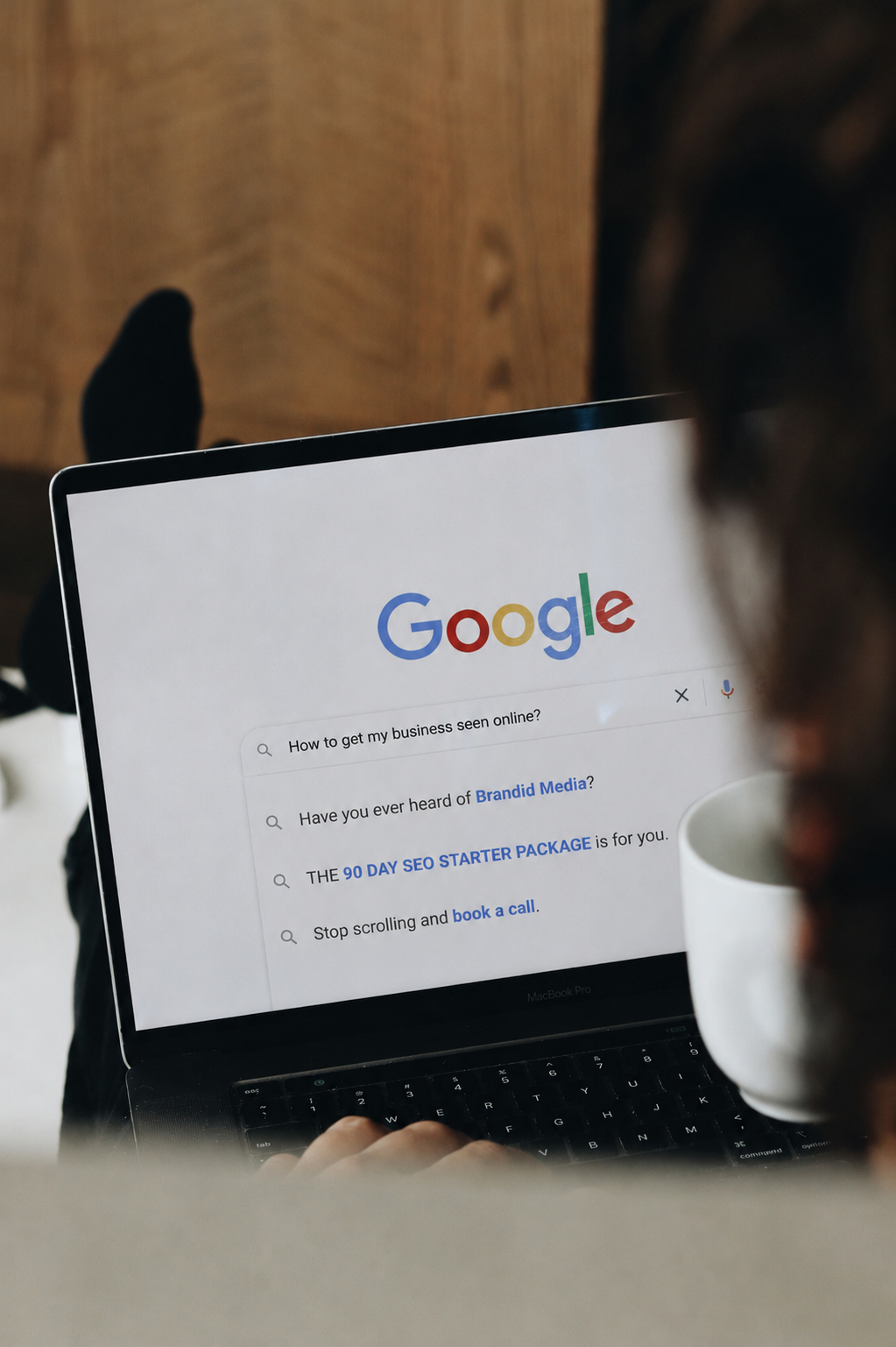 Person using a MacBook Pro with Google search page open, showing search queries related to online business visibility and SEO services.