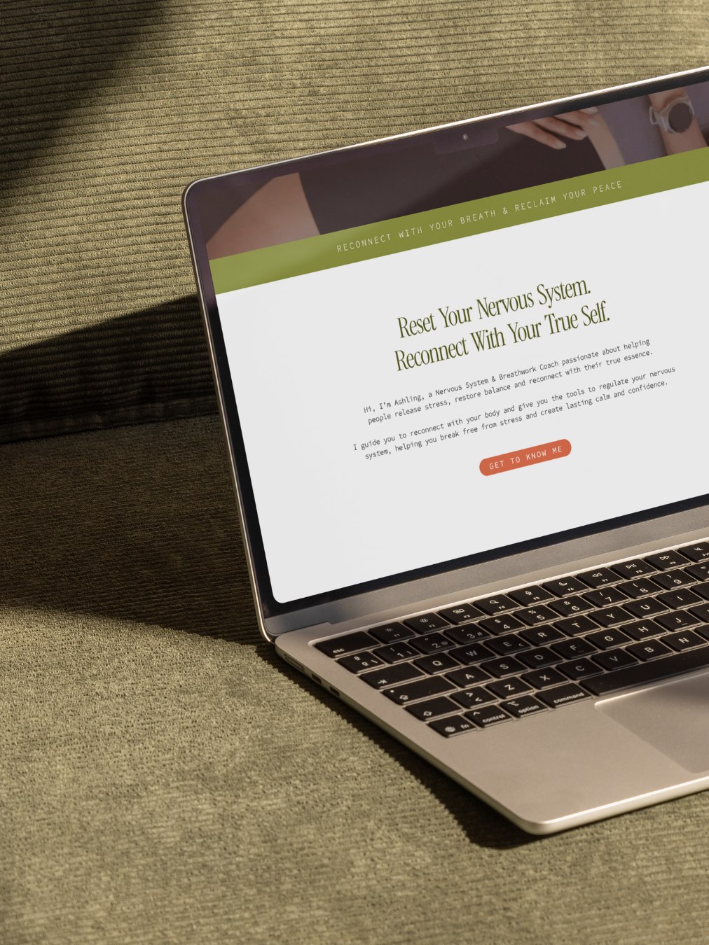 Open laptop on a textured green fabric surface displaying a webpage about resetting the nervous system and reconnecting with true self.