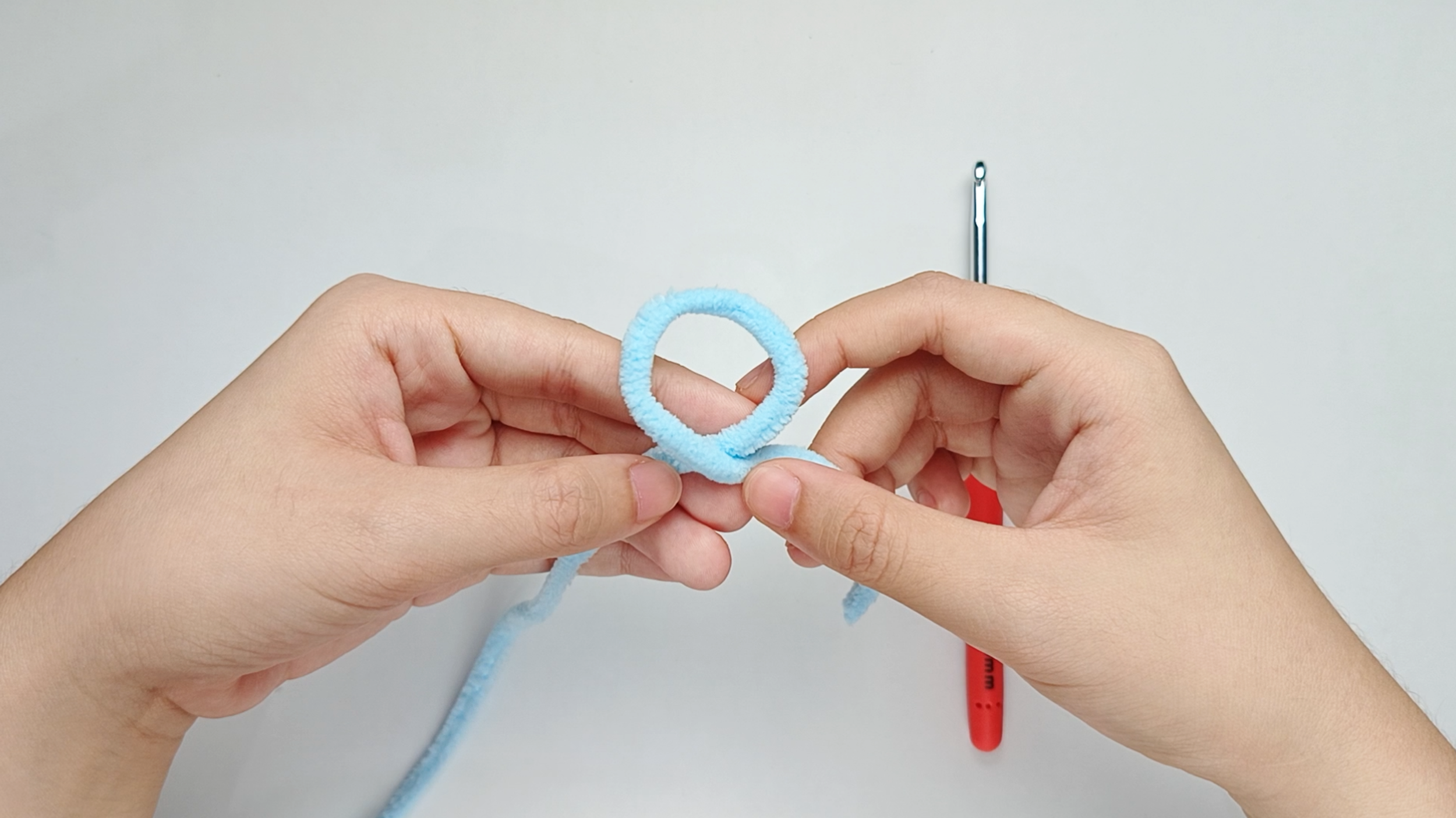 Make a loop: Cross the yarn tail in front of the working yarn to make a loop.
