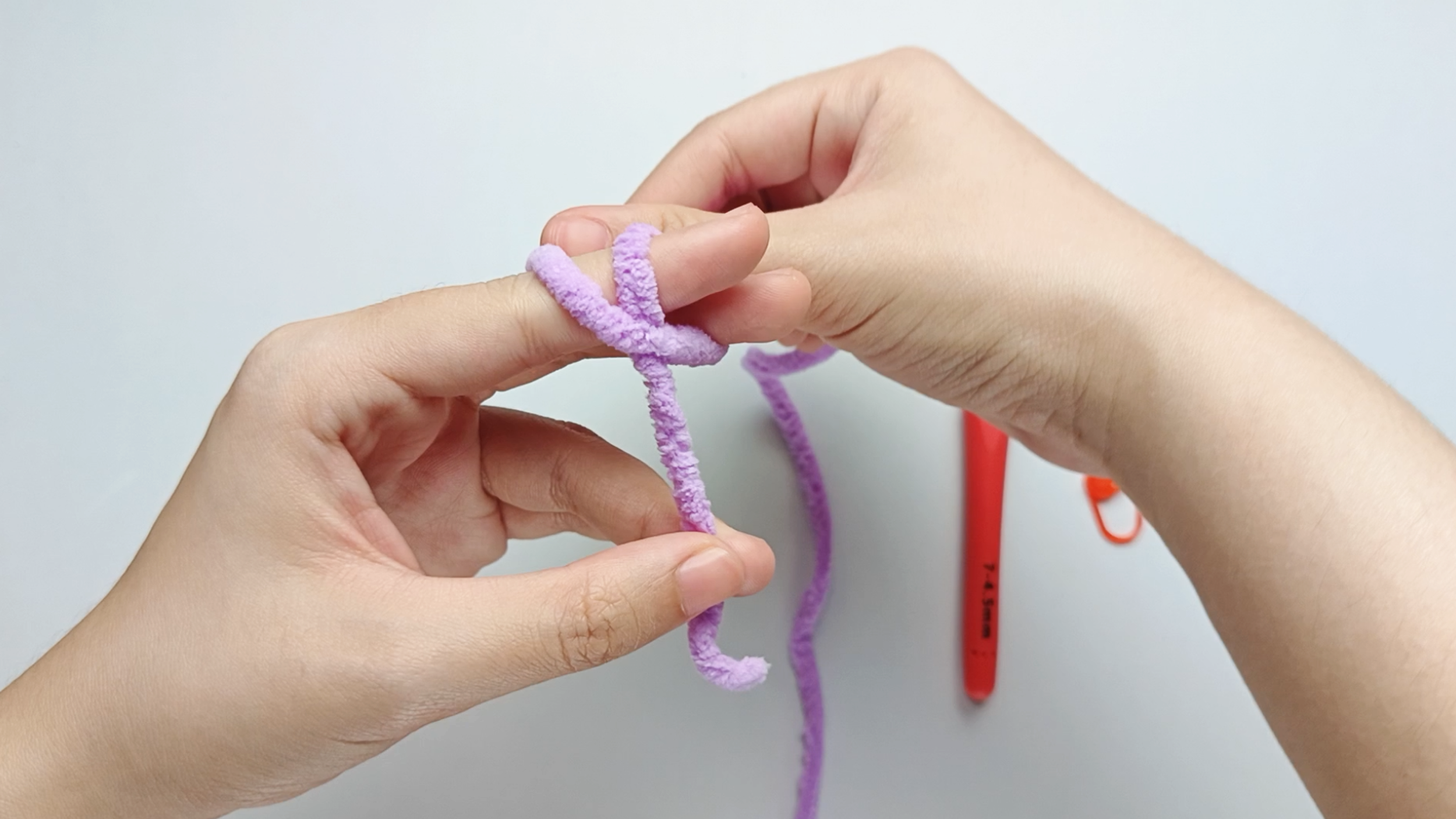 Cross into an X: Cross the working yarn over itself to form an “X” shape.