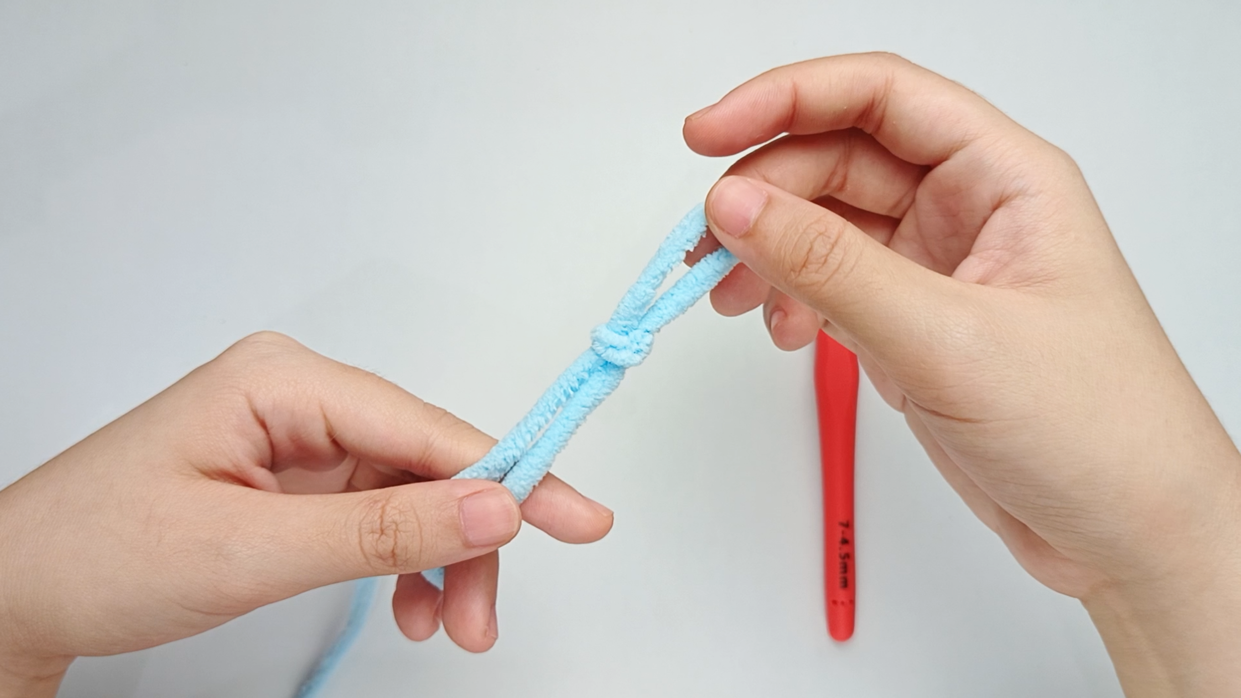 Tighten into a knot: Pull the strand in the center of the loop upward while you pull the yarn tail to tighten.