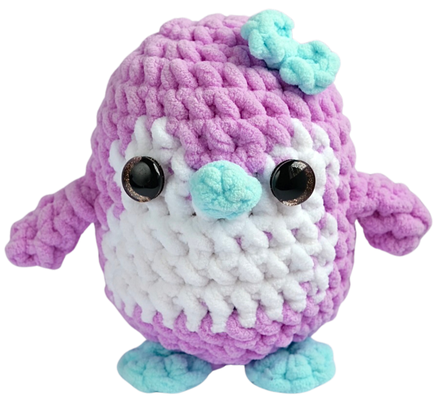 Pip the Penguin, a purple and white crochet penguin with a blue nose and a small blue bow.