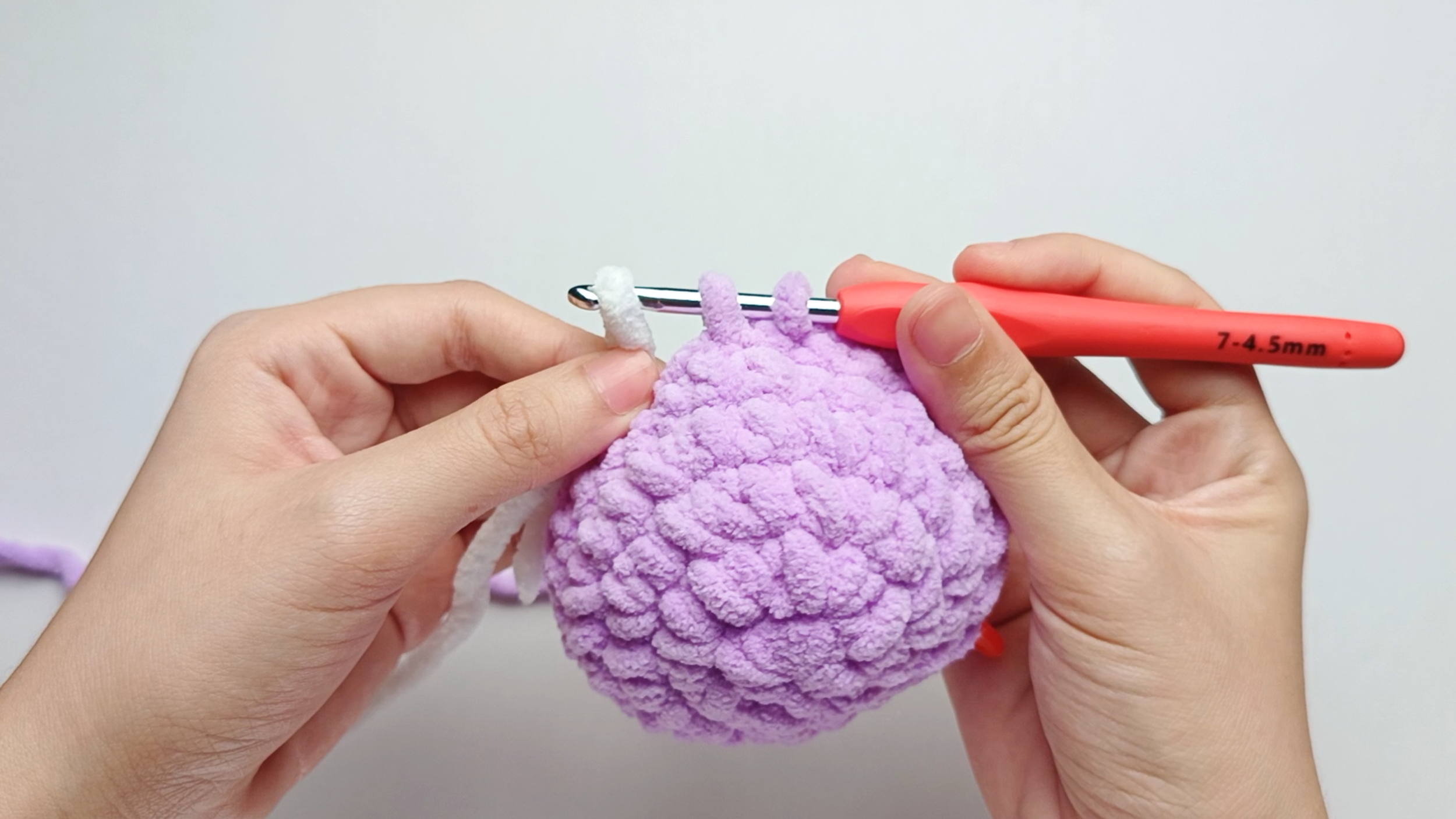 Add white yarn: Drape the white yarn over your hook. Pinch it with your left hand to make a snug loop on the hook. You'll now see three loops on your hook.