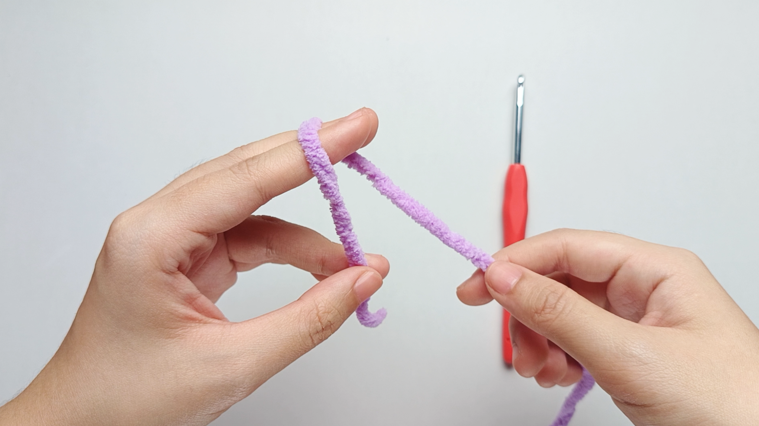 Wrap over your fingers: Bring the working yarn up and over your index and middle fingers, then down again toward your palm.