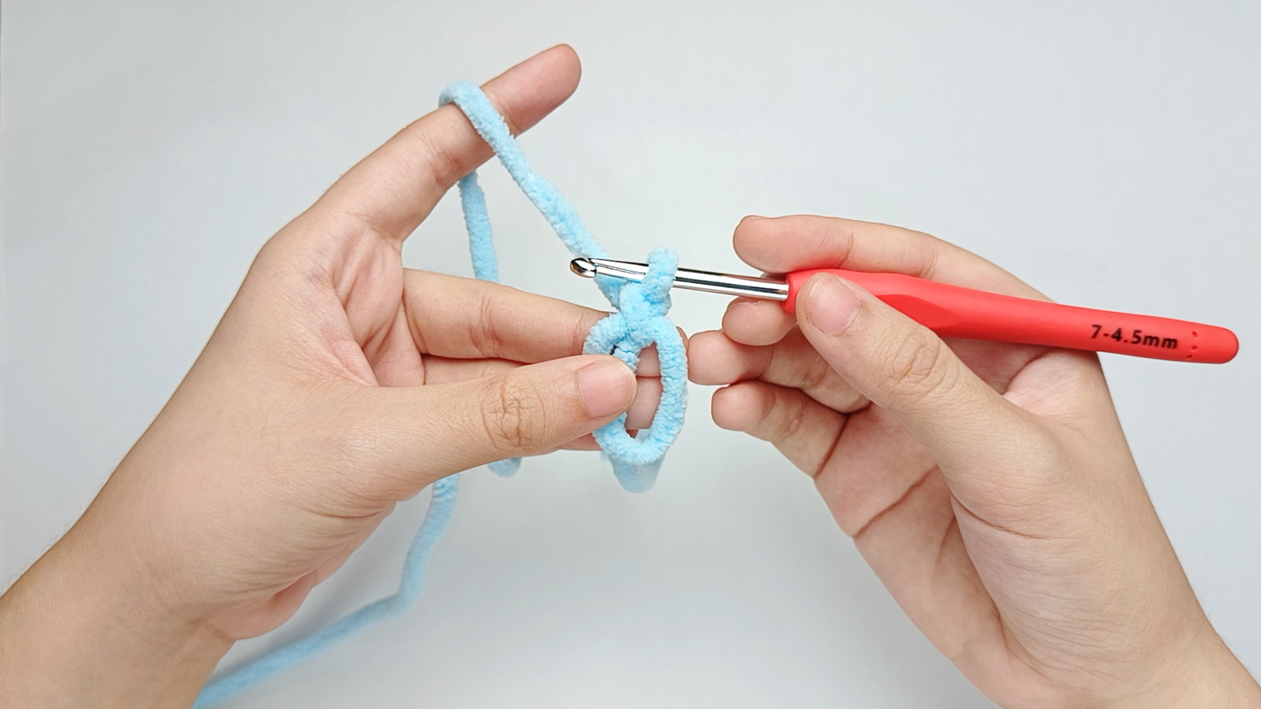Make a magic ring (MR): Follow the same magic-ring photos from the Body's Round 1 - from 'Hold the yarn tail' through 'Release the ring' - to make your magic ring (MR).