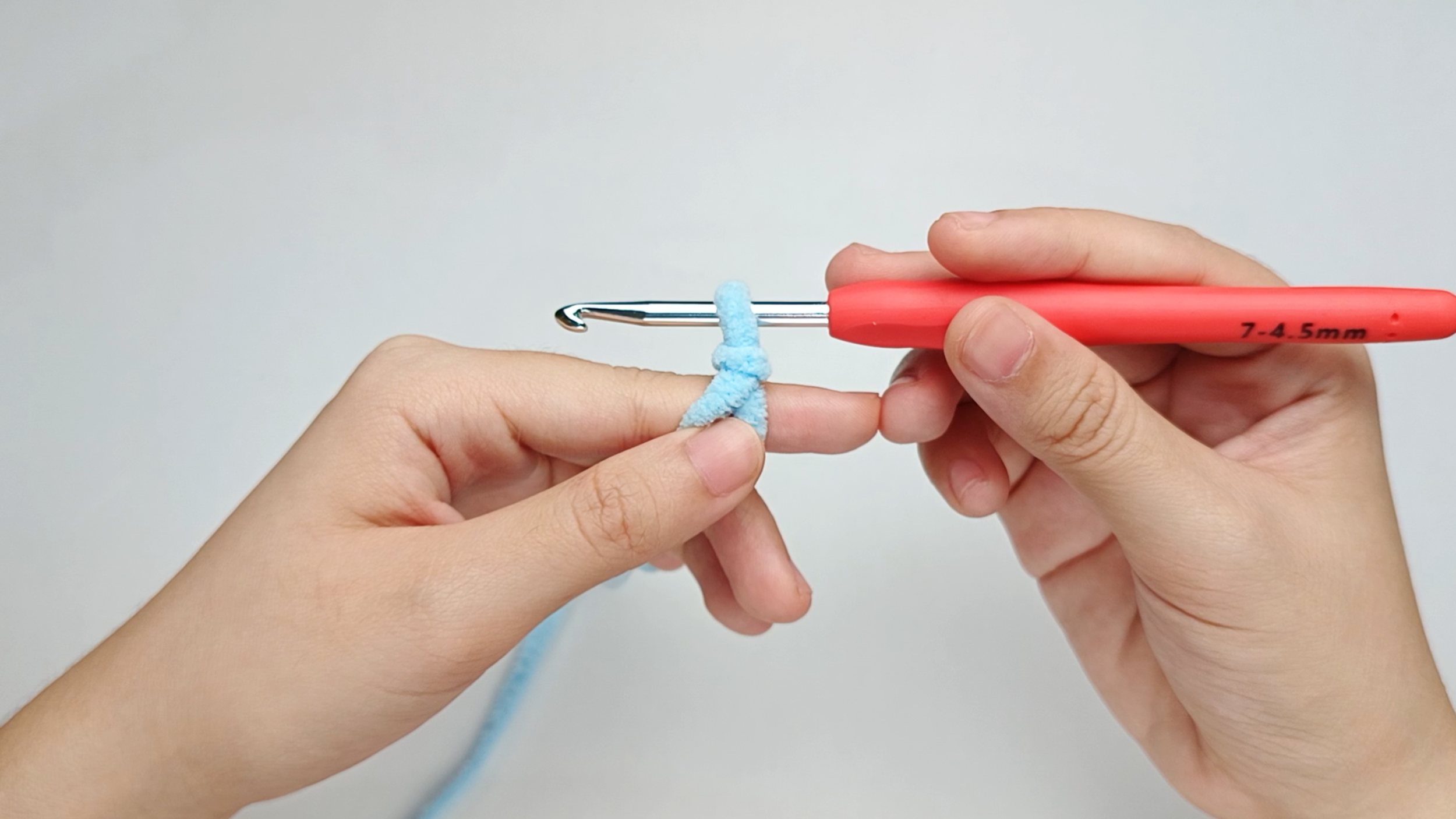 Hook into the loop: Slip your hook into the loop, then snug the loop up so it sits comfortably around the hook - not tight. Hold the yarn in place with your other hand.