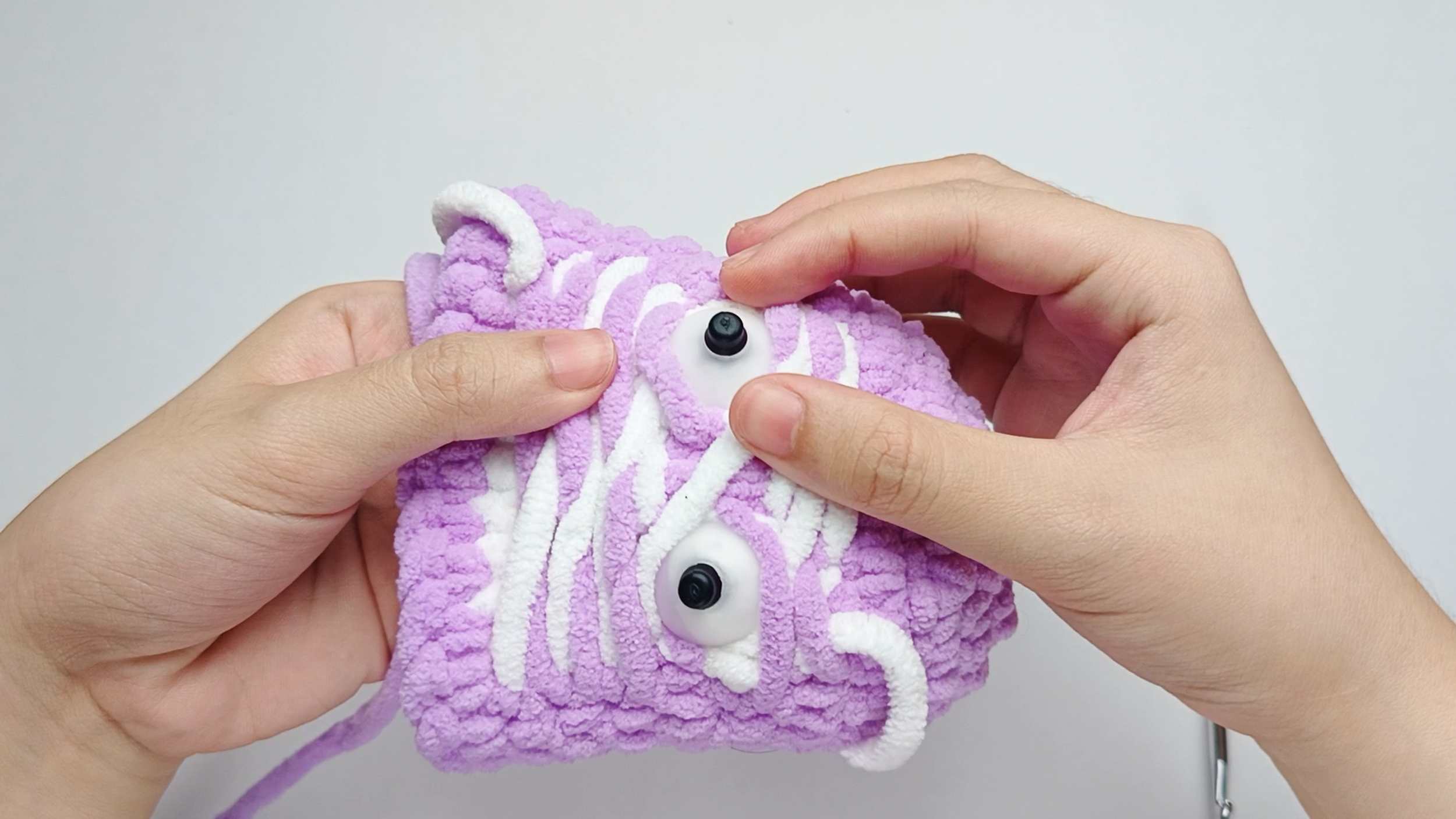 Add the backing: Turn your piece so you're working from the inside. Slide the backing onto the stem of each eye, flat side against the yarn.