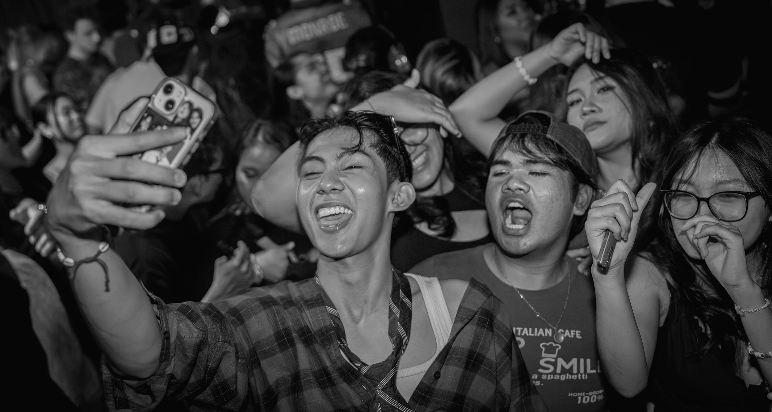 Black and white photo of a crowd of people taking a selfie together at a crowded event.