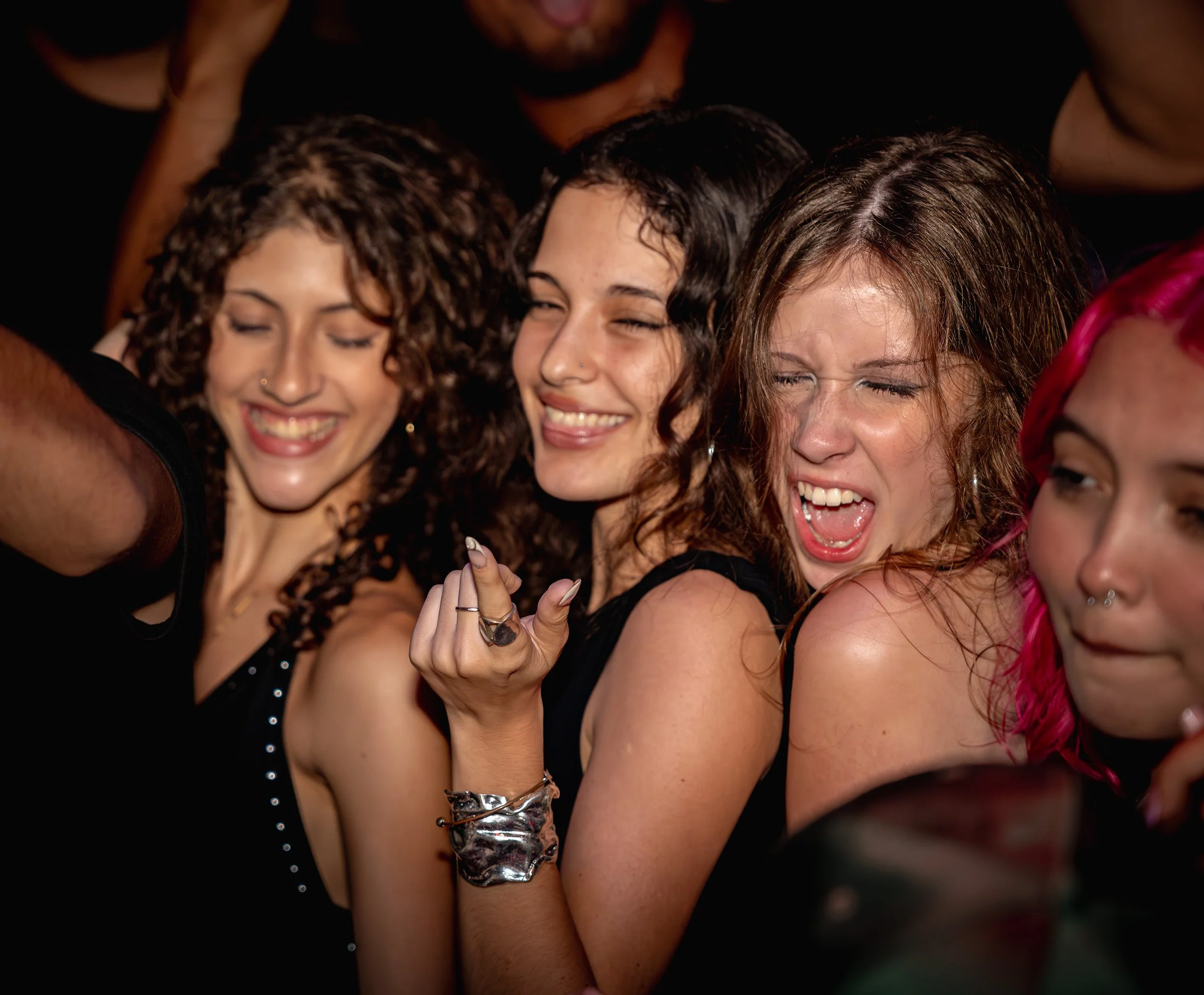 Close-up of people smiling and hugging, with focus on their faces and arms, celebrating together.