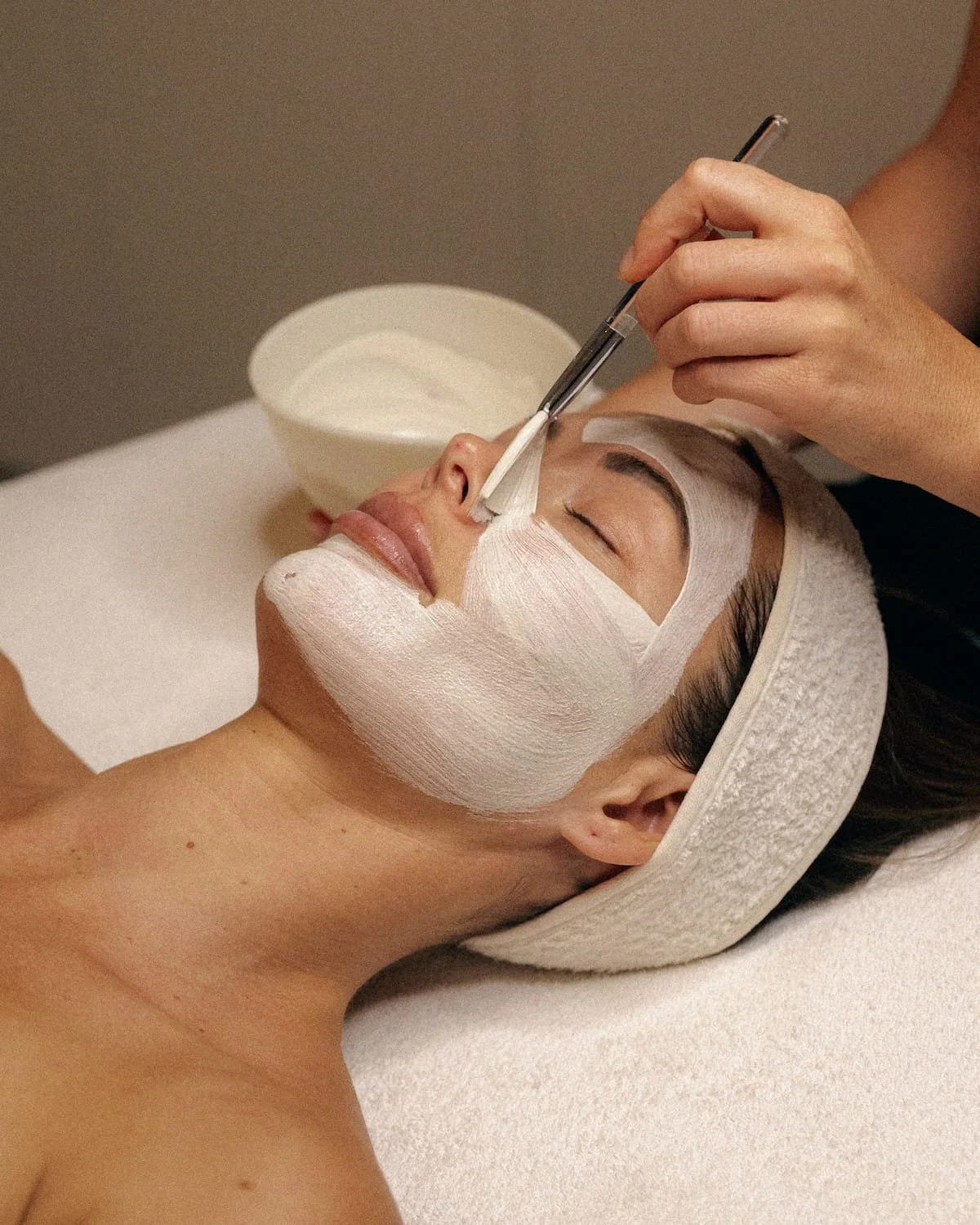 A luxury facial mask application in a serene clinical setting, highlighting the Glow aesthetic and skin health treatments.