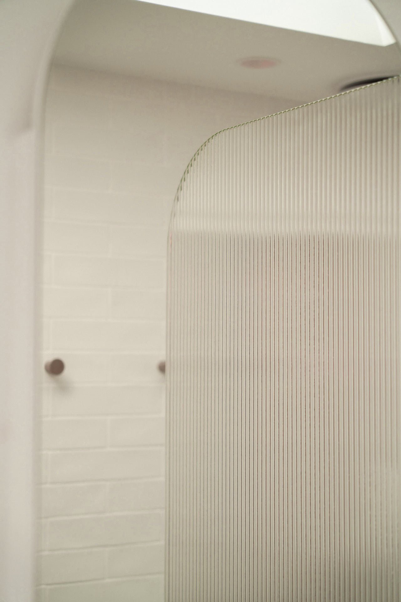 Close-up view of a light-colored wall with a textured, striped surface and small dark circular objects mounted on the wall.