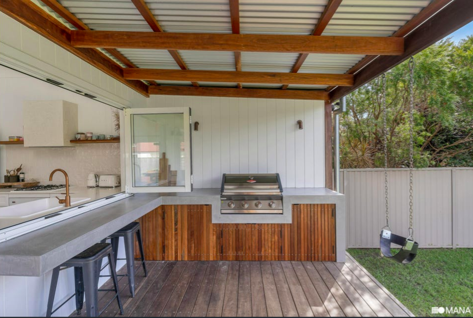 Outdoor kitchen with a grill, countertop, and a swing in a backyard