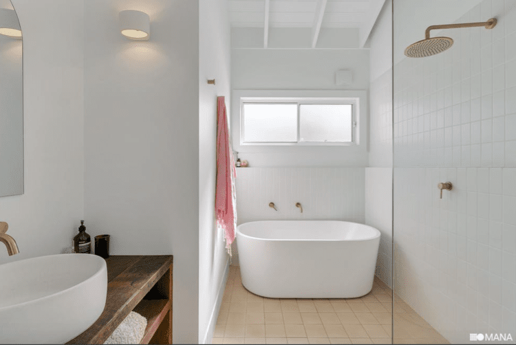 Modern bathroom with white walls, a freestanding bathtub, a walk-in shower with a rain showerhead, a window, and a wooden vanity with a vessel sink.