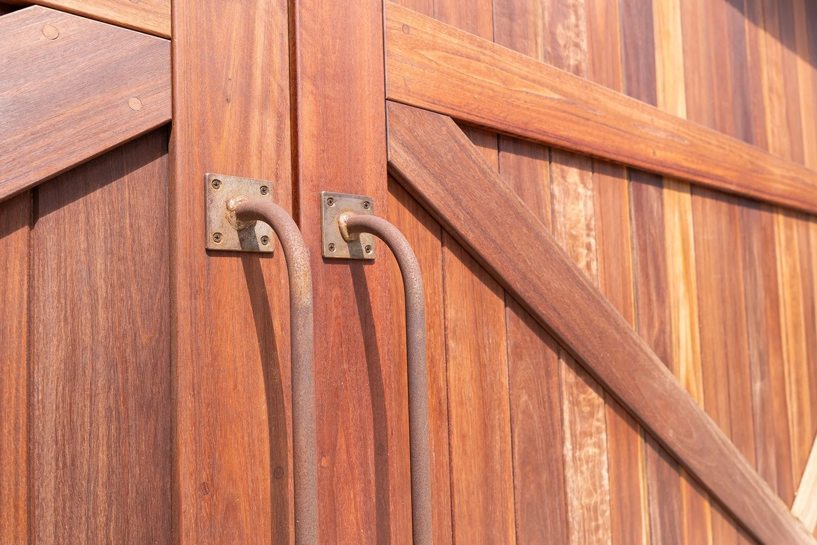 A close-up view of rusted metal handles on a wooden barn door.