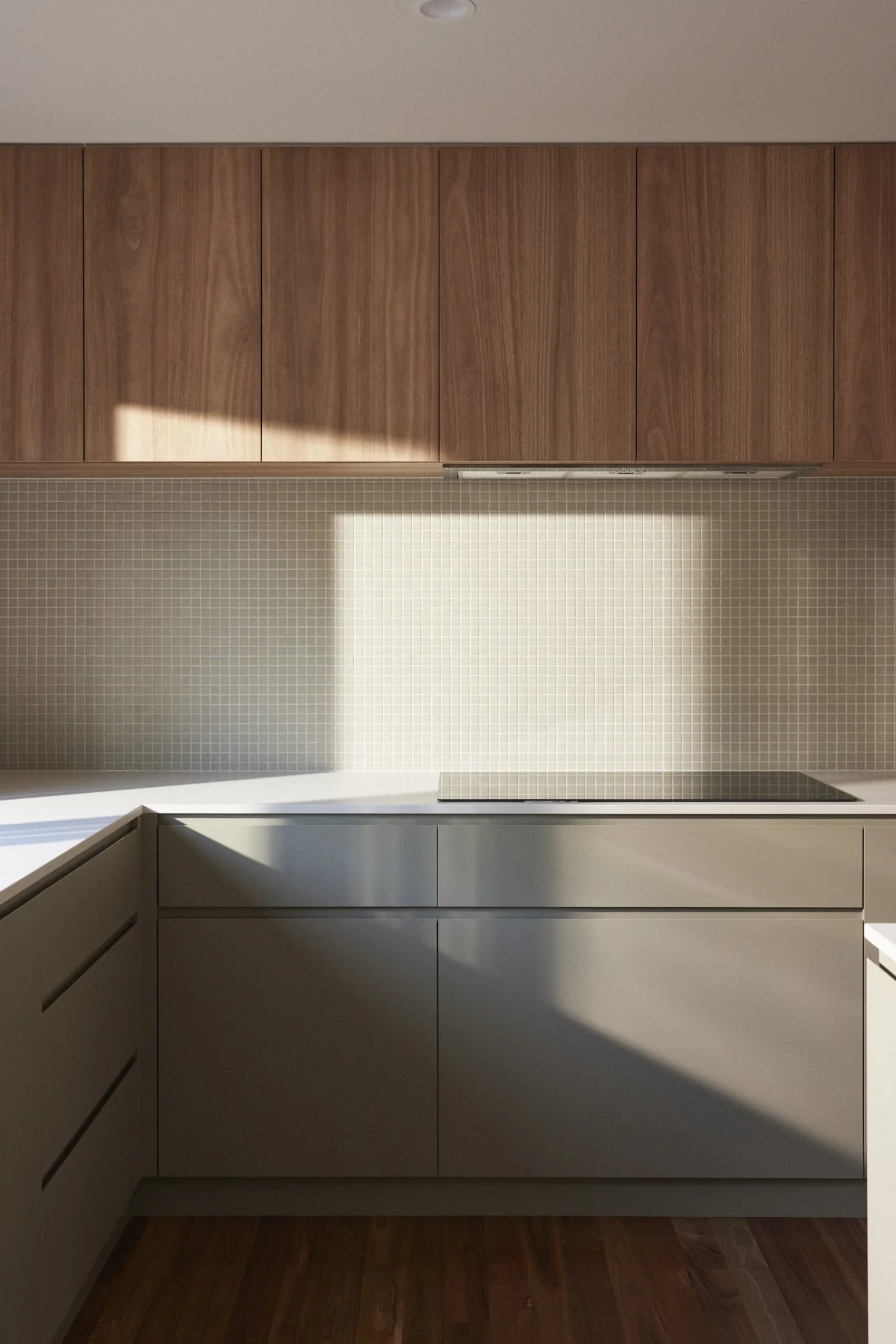 Modern kitchen with white cabinetry, wooden upper cabinets, tiled backsplash, and dark wood flooring.