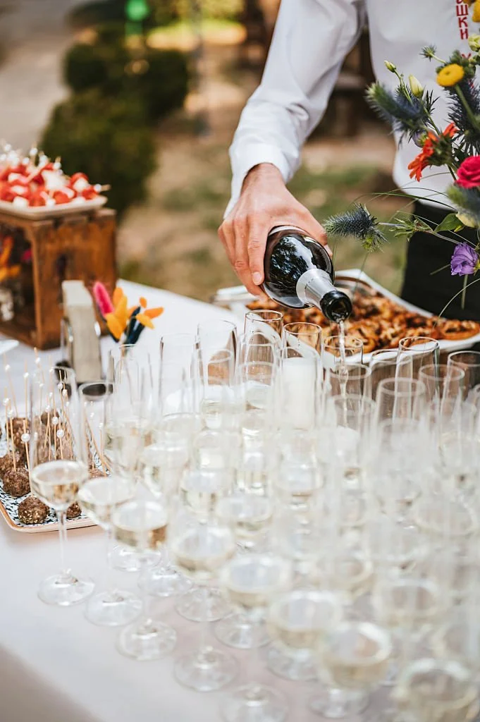 Une personne verse du vin dans des flûtes à champagne lors d'une célébration en plein air.