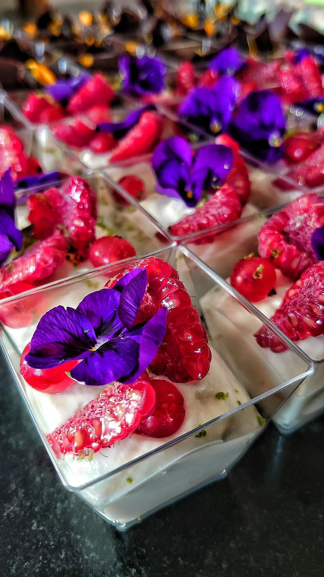 Dessert en verrine avec des fraises, des mûres et des violettes pour la décoration.