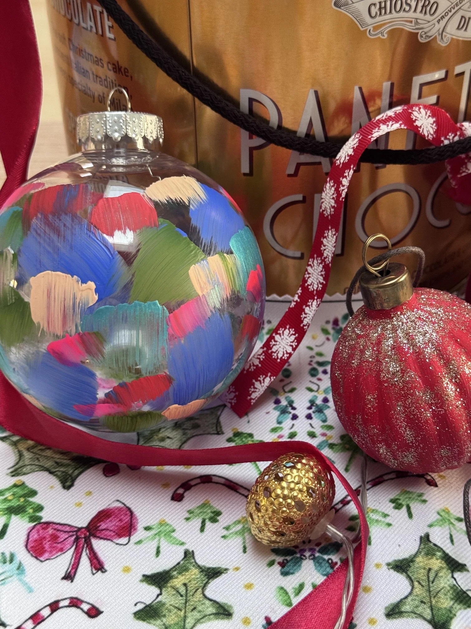 selection of brightly coloured hand painted christmas baubles set on a decorated festive cloth