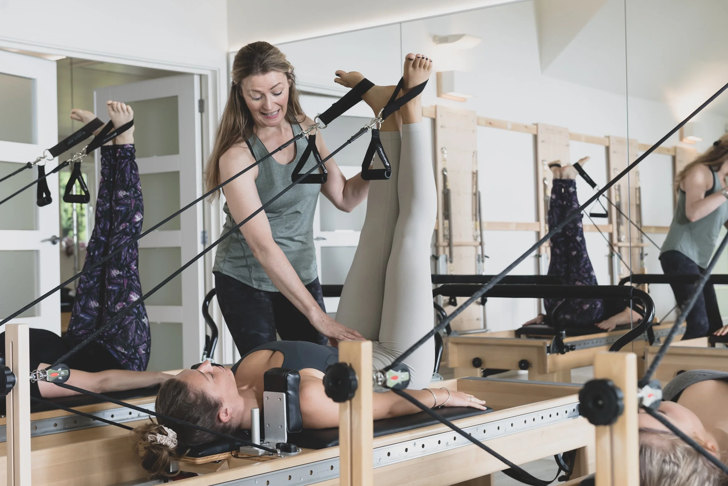 Women practicing Pilates using specialized reformer machines in a fitness studio.