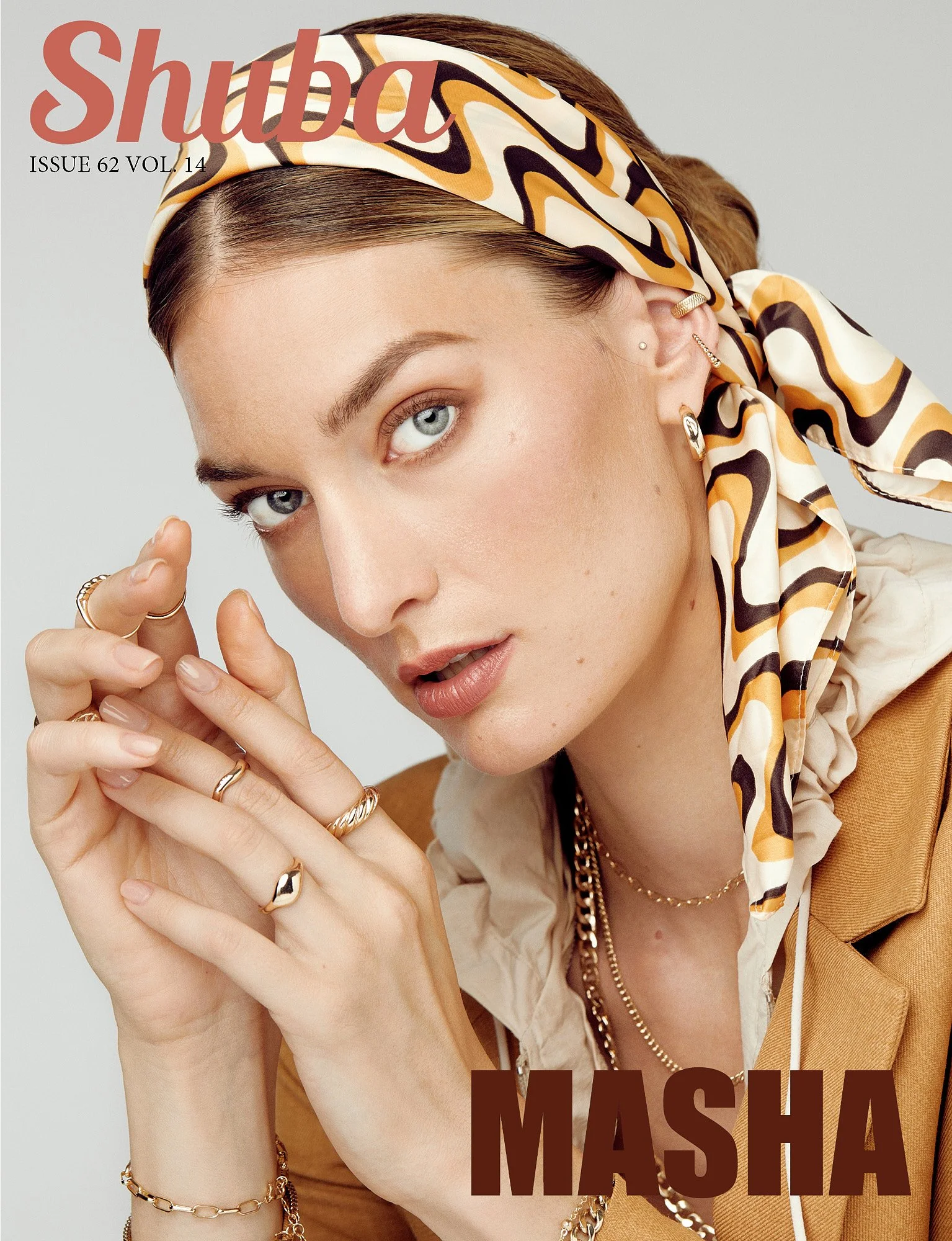 Close-up of a woman with blue eyes, wearing jewelry and a patterned scarf on her head, on the cover of Shuba magazine.