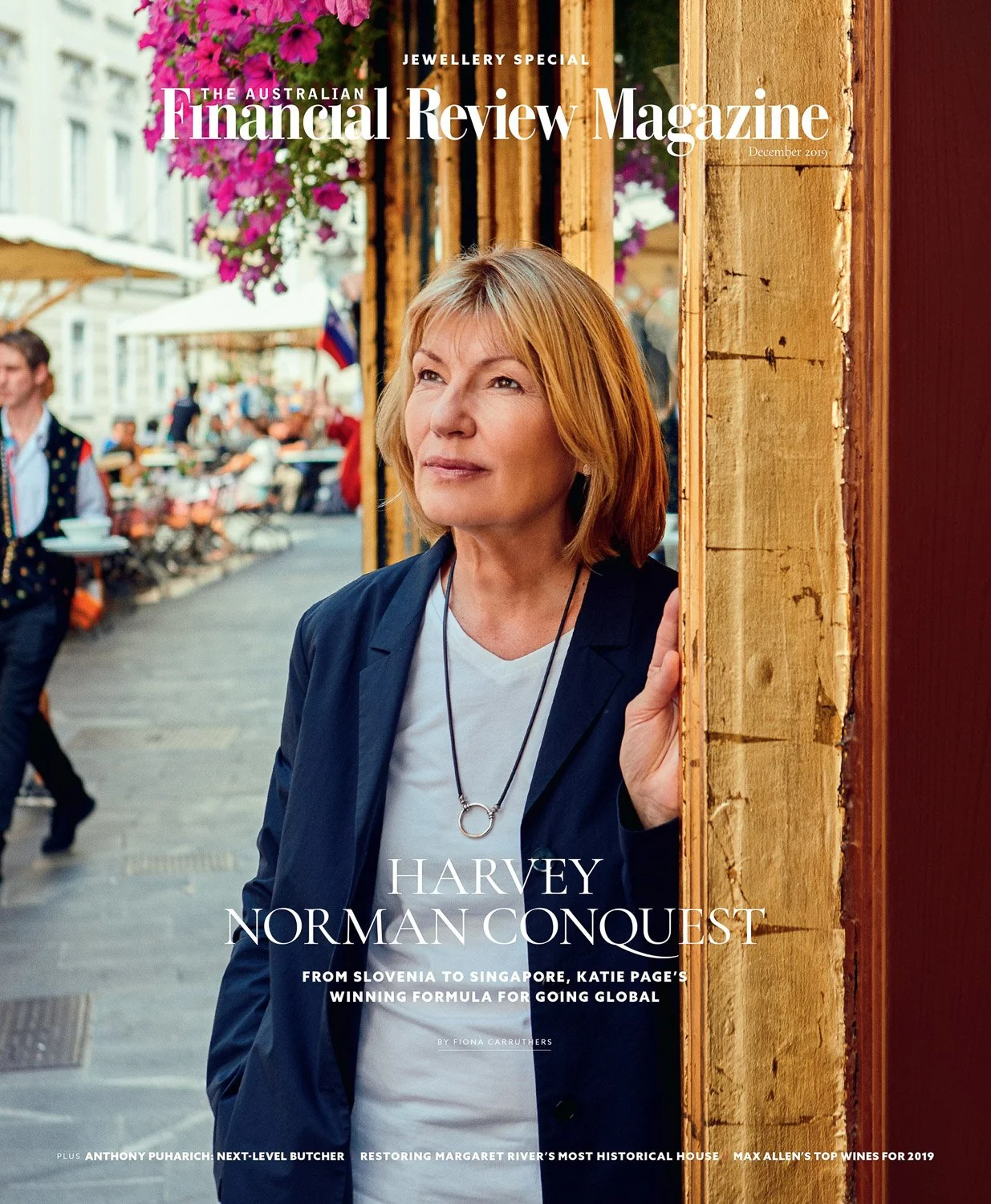 Cover of The Australian Financial Review Magazine featuring a woman with blonde hair wearing a black blazer and white shirt, standing on a street with outdoor seating and flowers in the background.