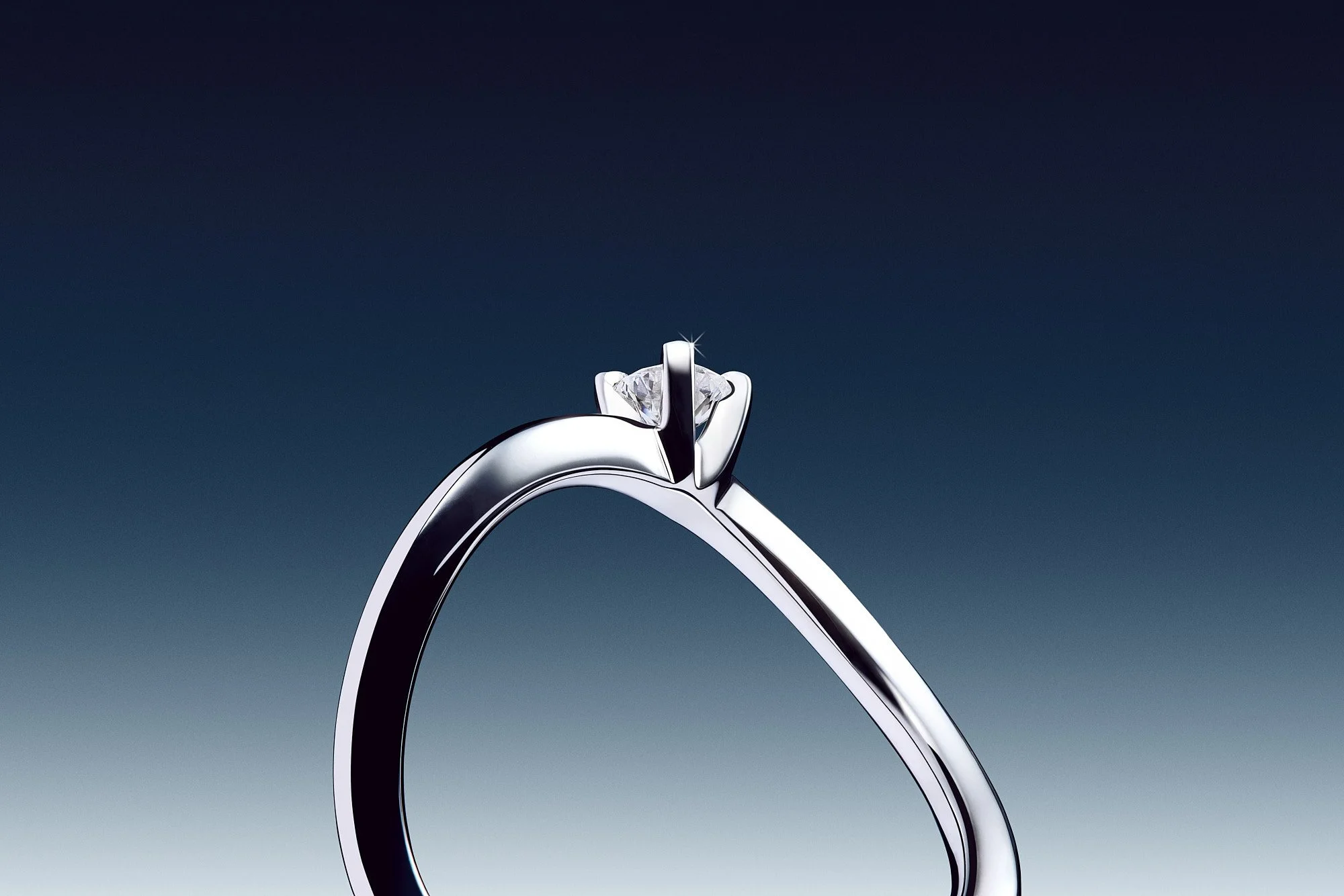 Close-up of a diamond engagement ring with a solitaire diamond on a silver band against a dark gradient background.