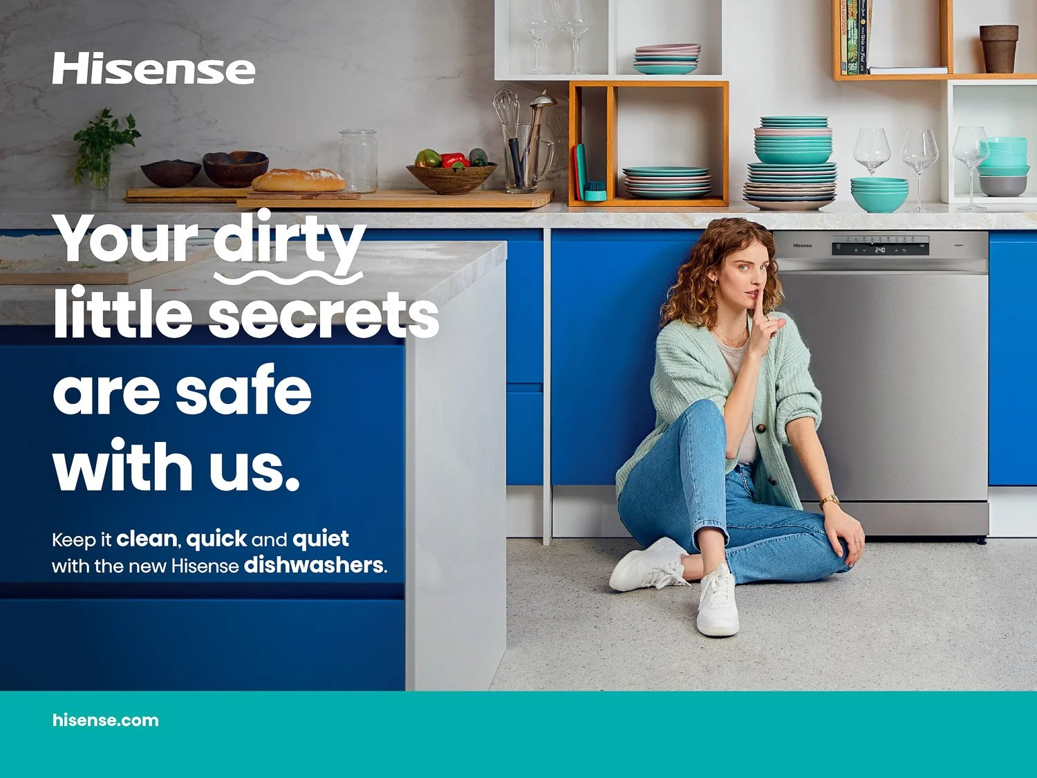 A woman sitting on the kitchen floor next to a dishwasher, with kitchen cabinets and shelves behind her. The image has text promoting Hisense dishwashers.