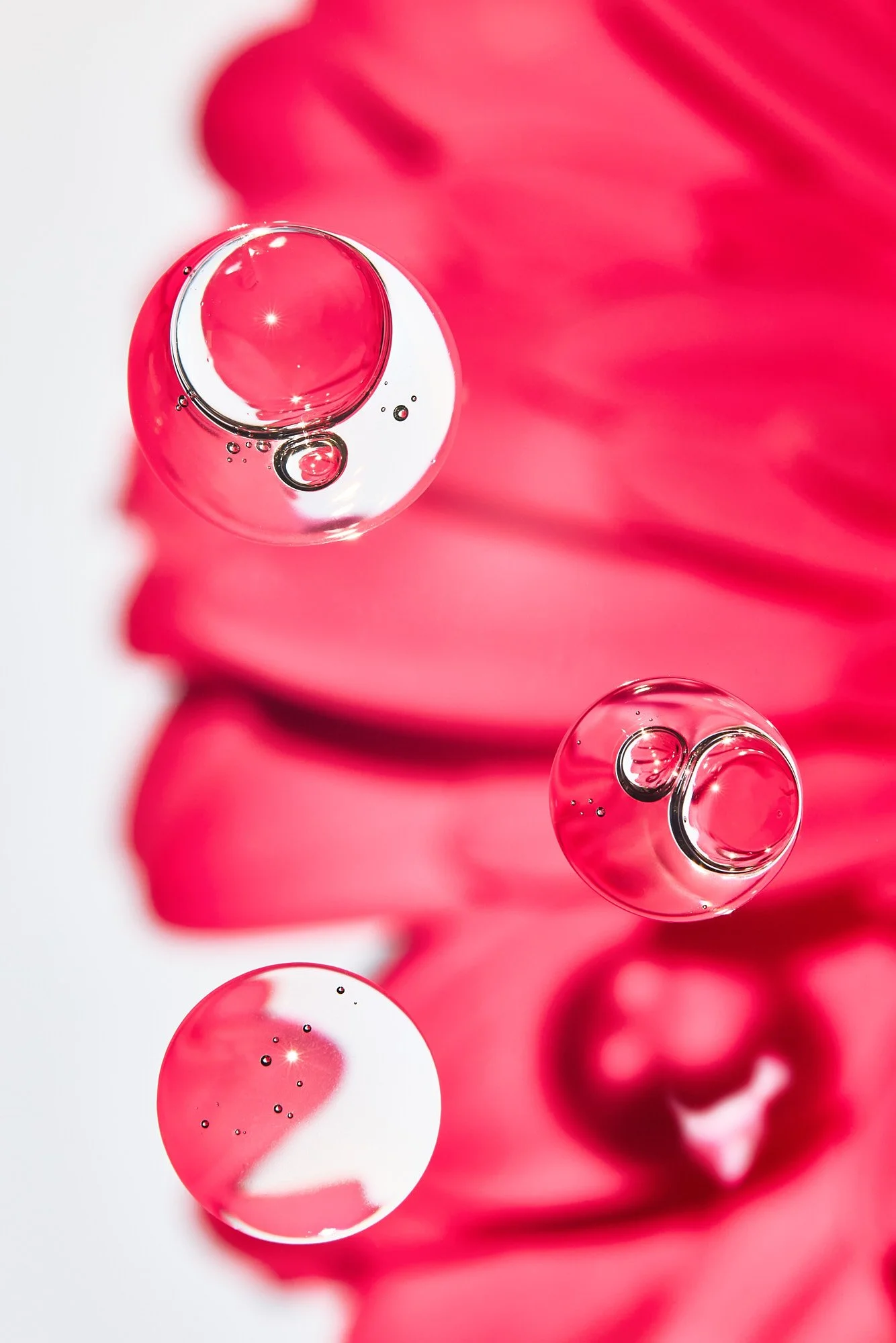 Close-up of pink bubbles on a clear surface, with a pink background.
