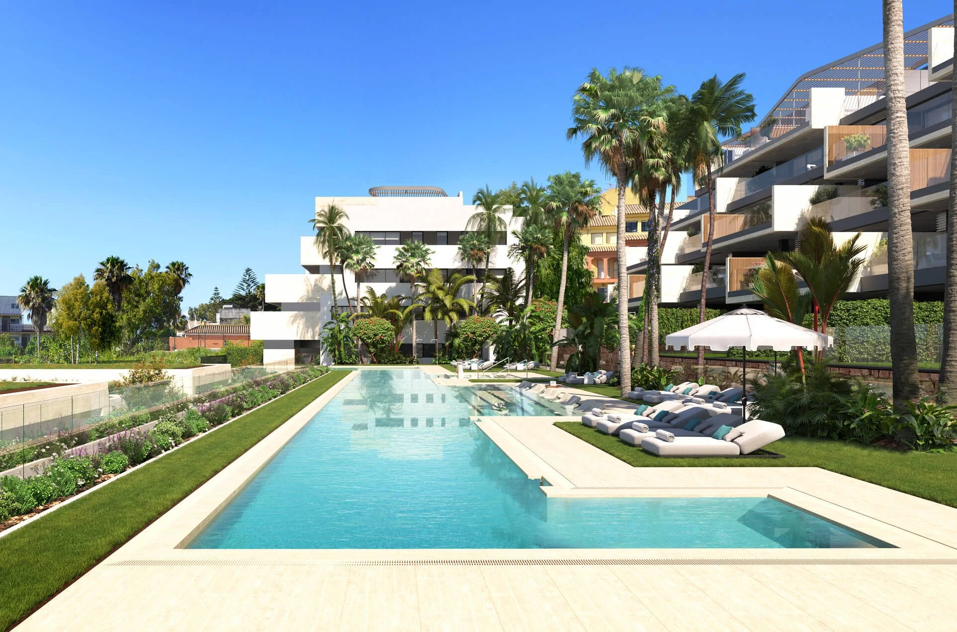 Luxury residential pool area with lounge chairs, umbrellas, lush greenery, palm trees, modern apartment buildings, and a clear blue sky.