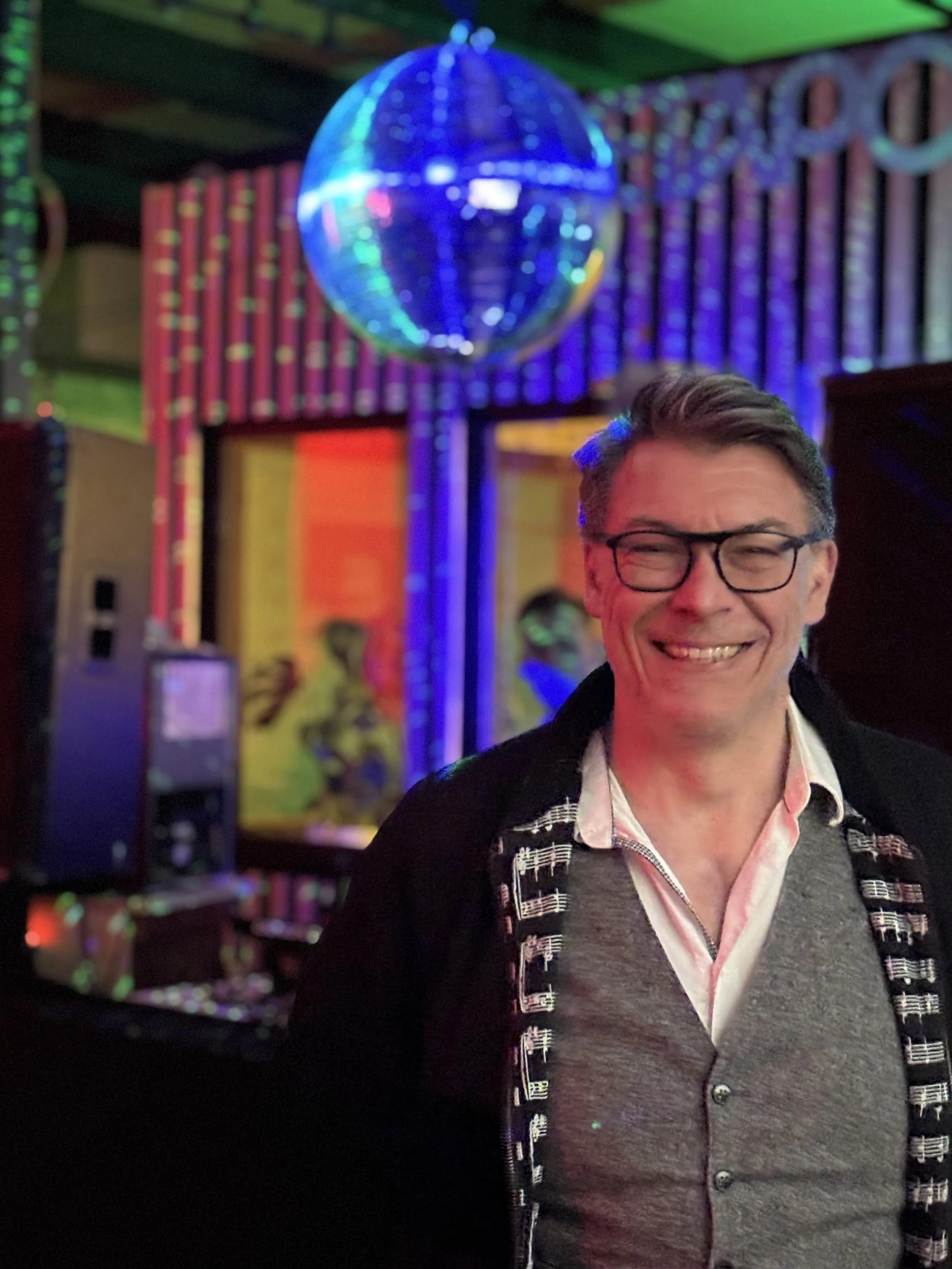 Porträtfoto von Björn Döring, Kurator der Fête de la Musique Berlin, vor einem bunten Bühnen-Hintergrund mit Discokugel
