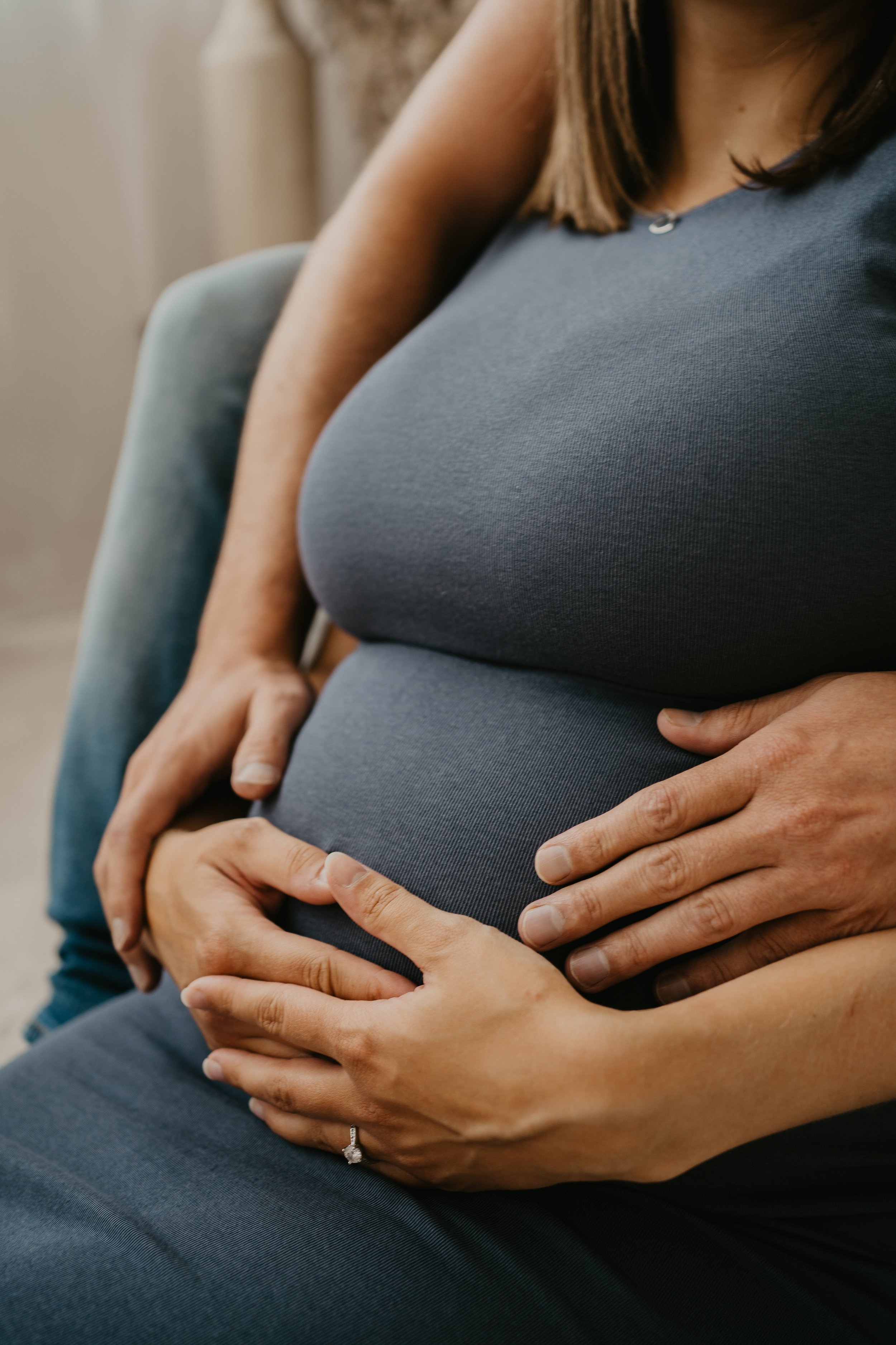 Mehrere Menschen umarmen eine schwangere Frau, die ihren Bauch hält.