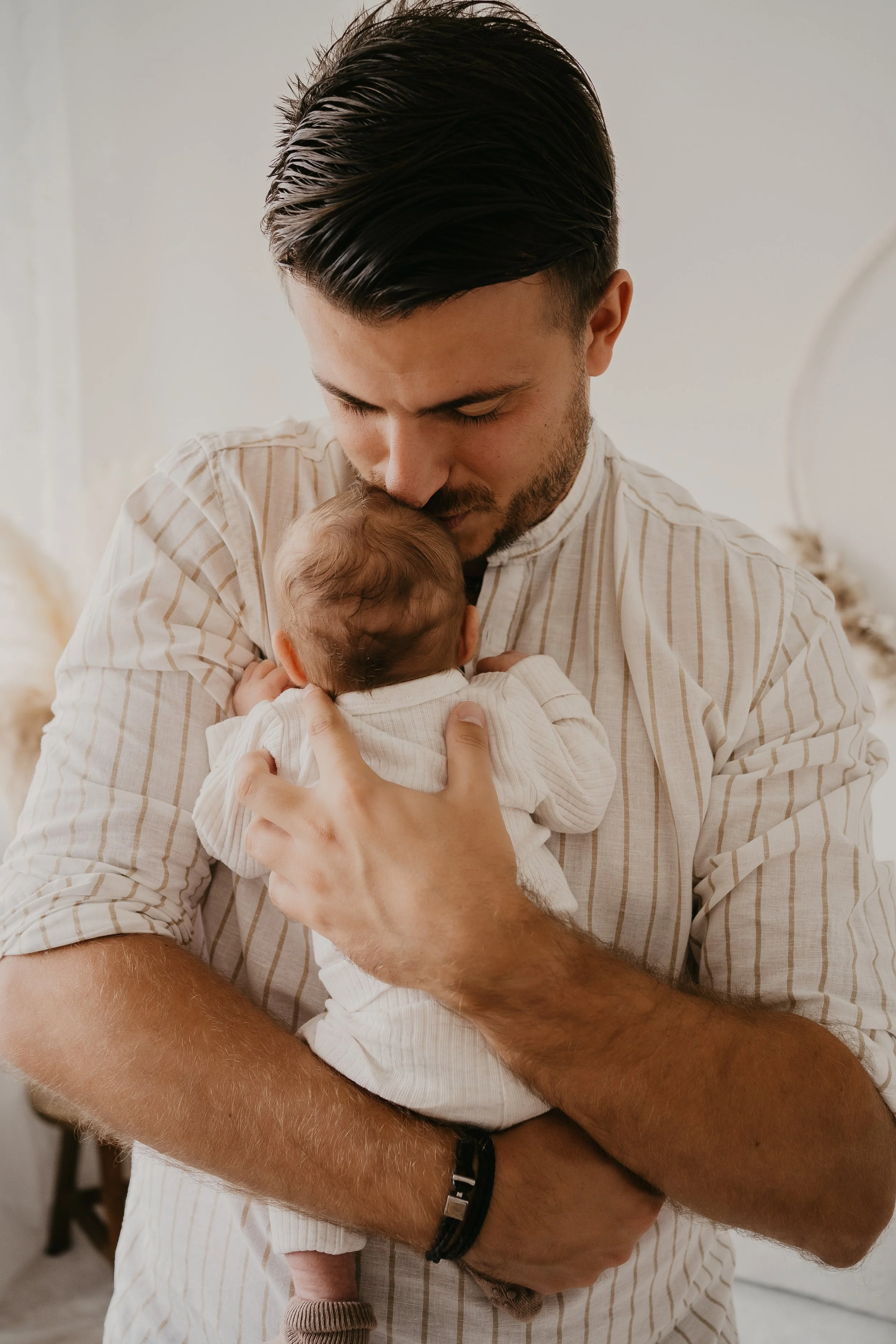 Ein Mann hält ein Baby im Arm und kümmert sich liebevoll um es.