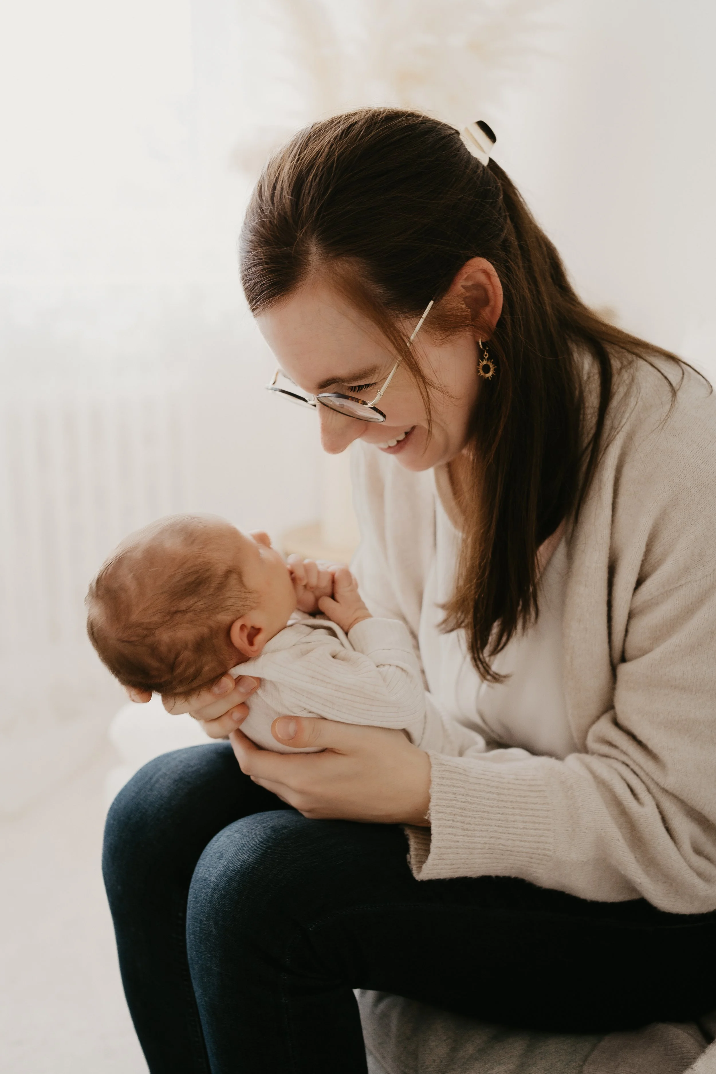 Eine Frau hält ein Baby liebevoll im Arm und lächelt.