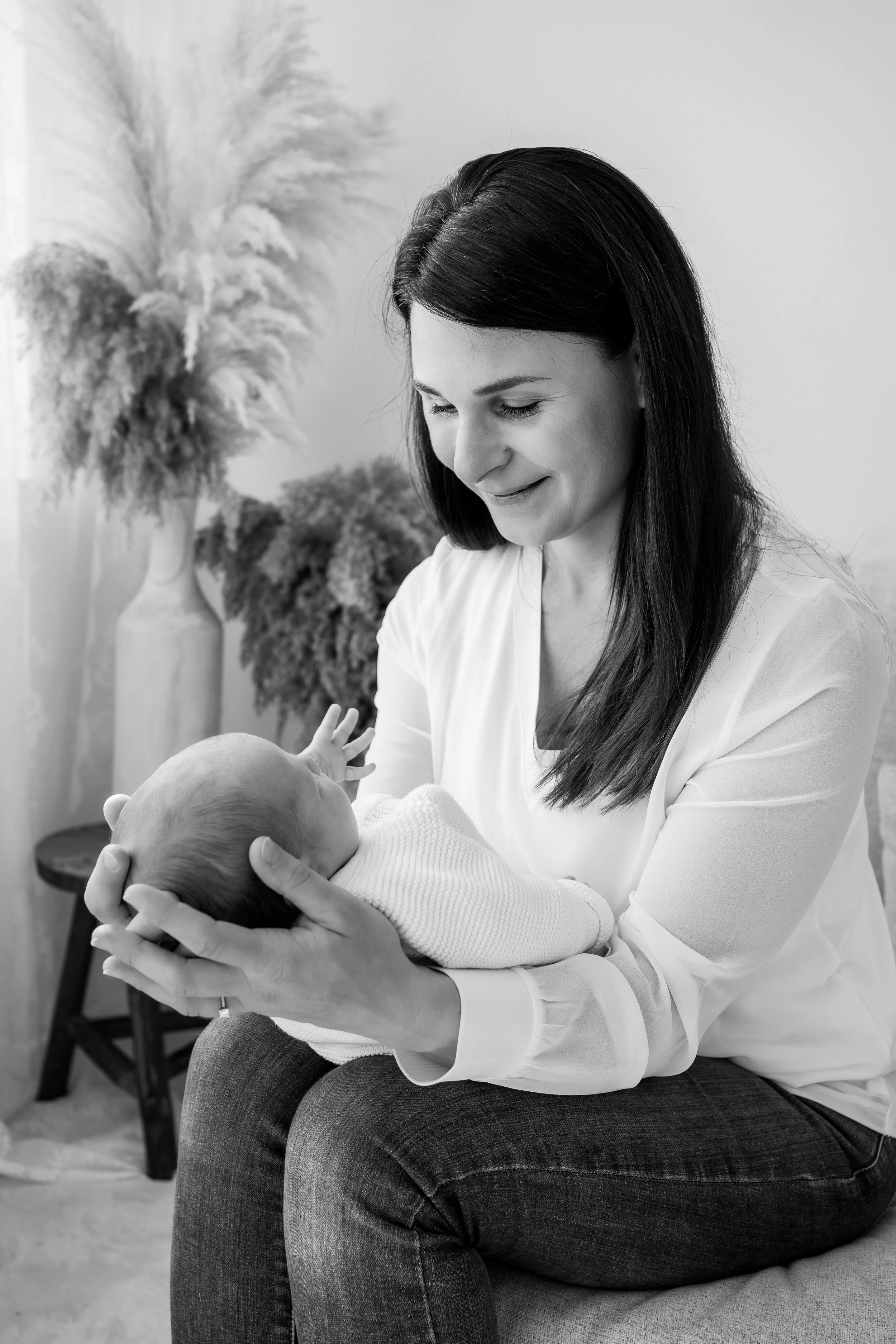 Eine Frau hält ein Baby liebevoll im Arm, in einer gemütlichen Umgebung mit Dekorationen im Hintergrund.