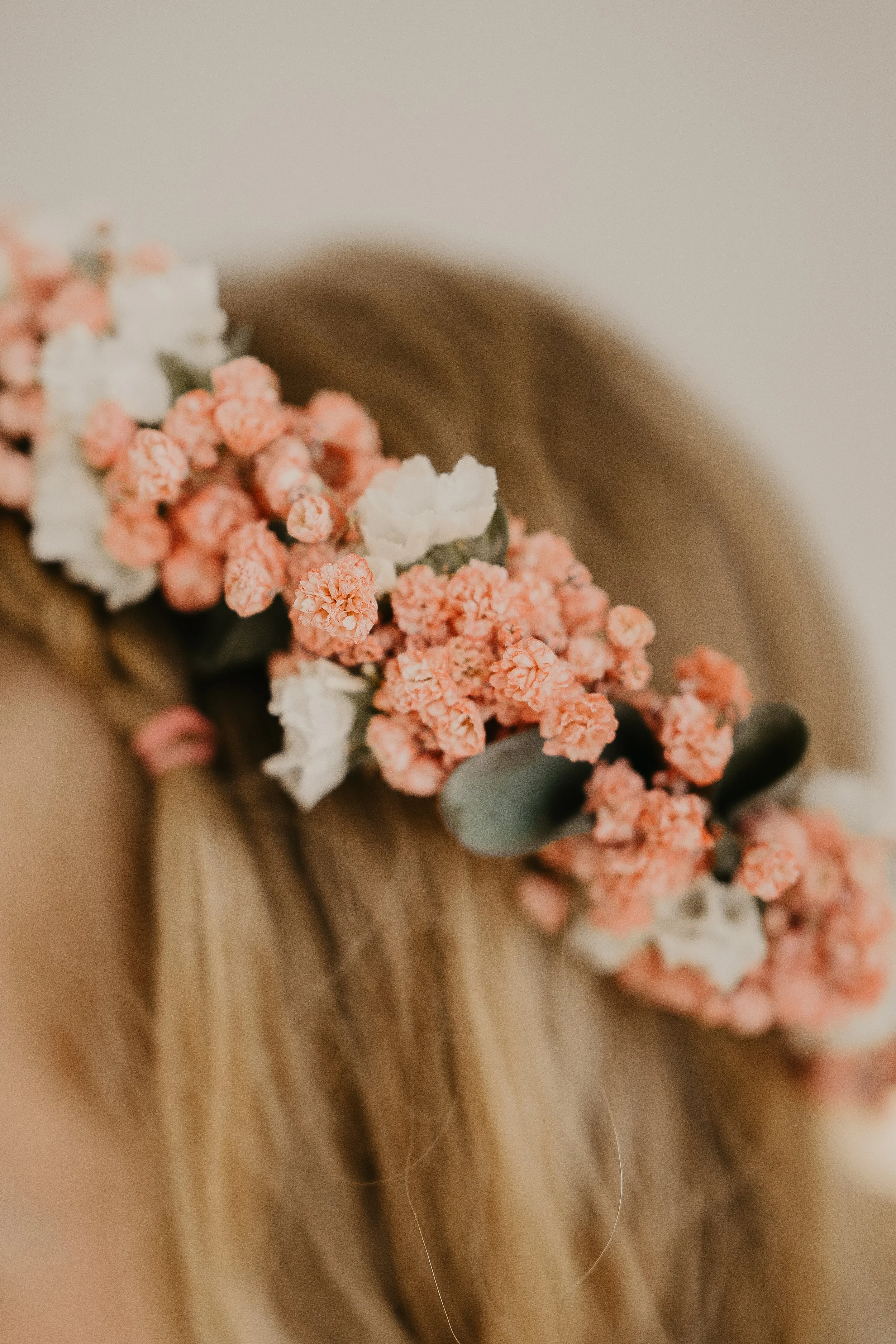 Nahaufnahme eines Haar-Haar-Kranzes mit weißen und rosa Blumen auf blondem Haar.