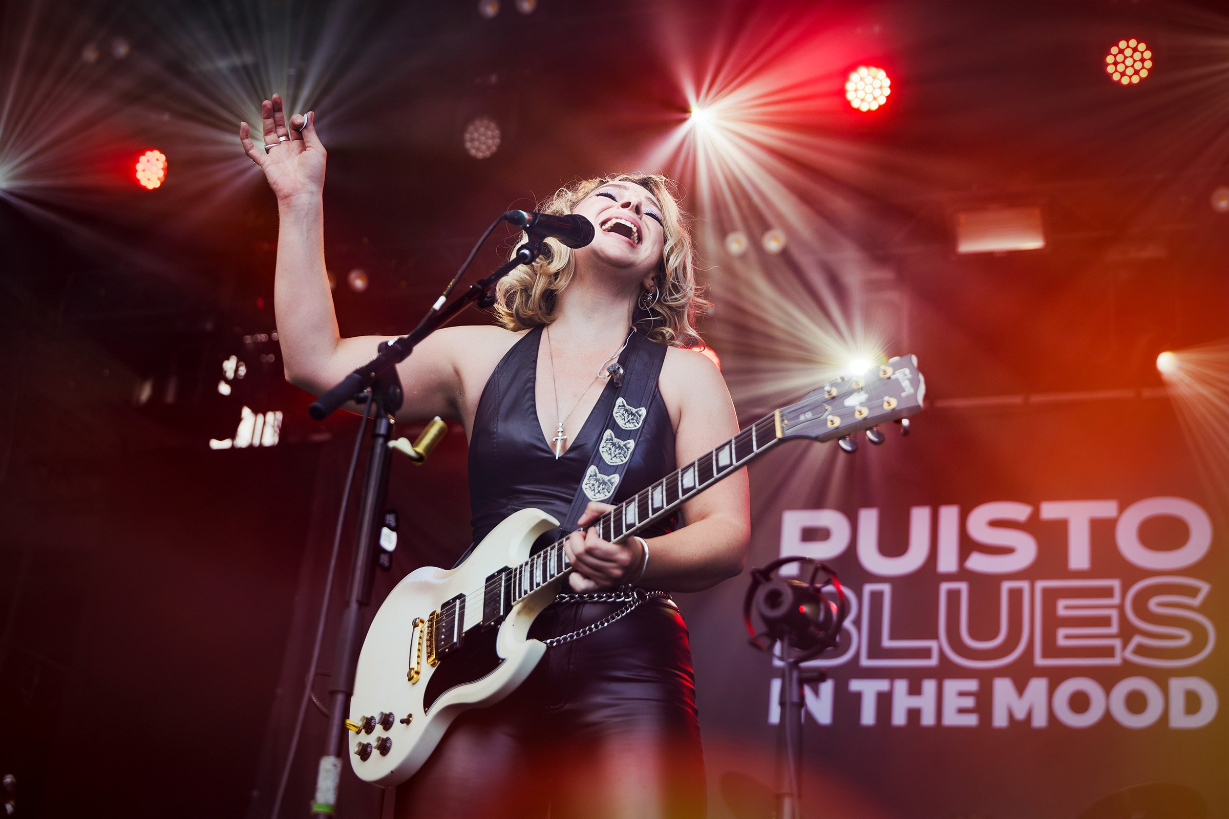 Samantha Fish singing and playing guitar under red stage lights at Puistoblues Festival in Finland, 2026.