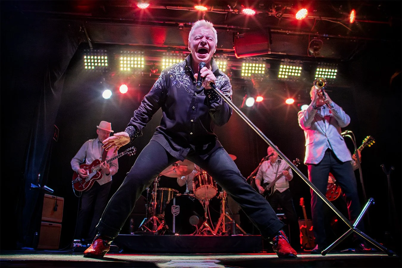 Jerry Williams in a powerful wide-legged stage pose during a live concert in Stockholm, Sweden, 2016.