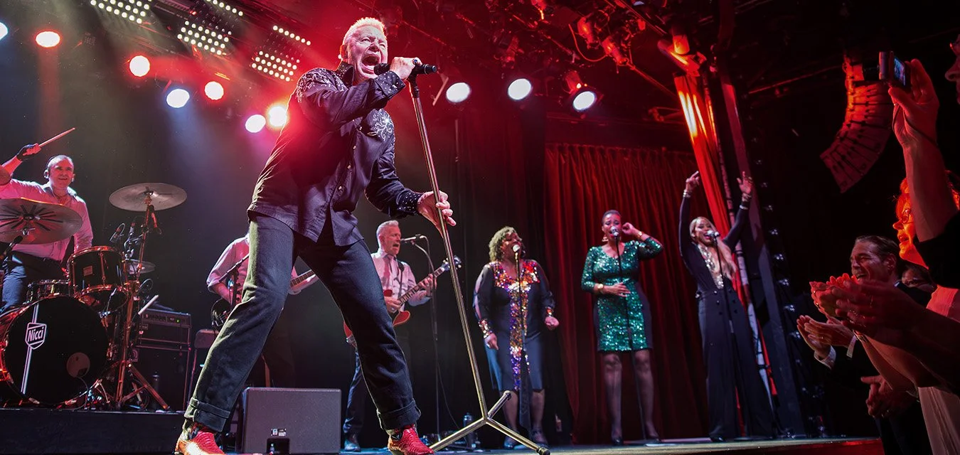 Jerry Williams singing on stage with backing vocalists during a live concert in Stockholm, Sweden, 2016.