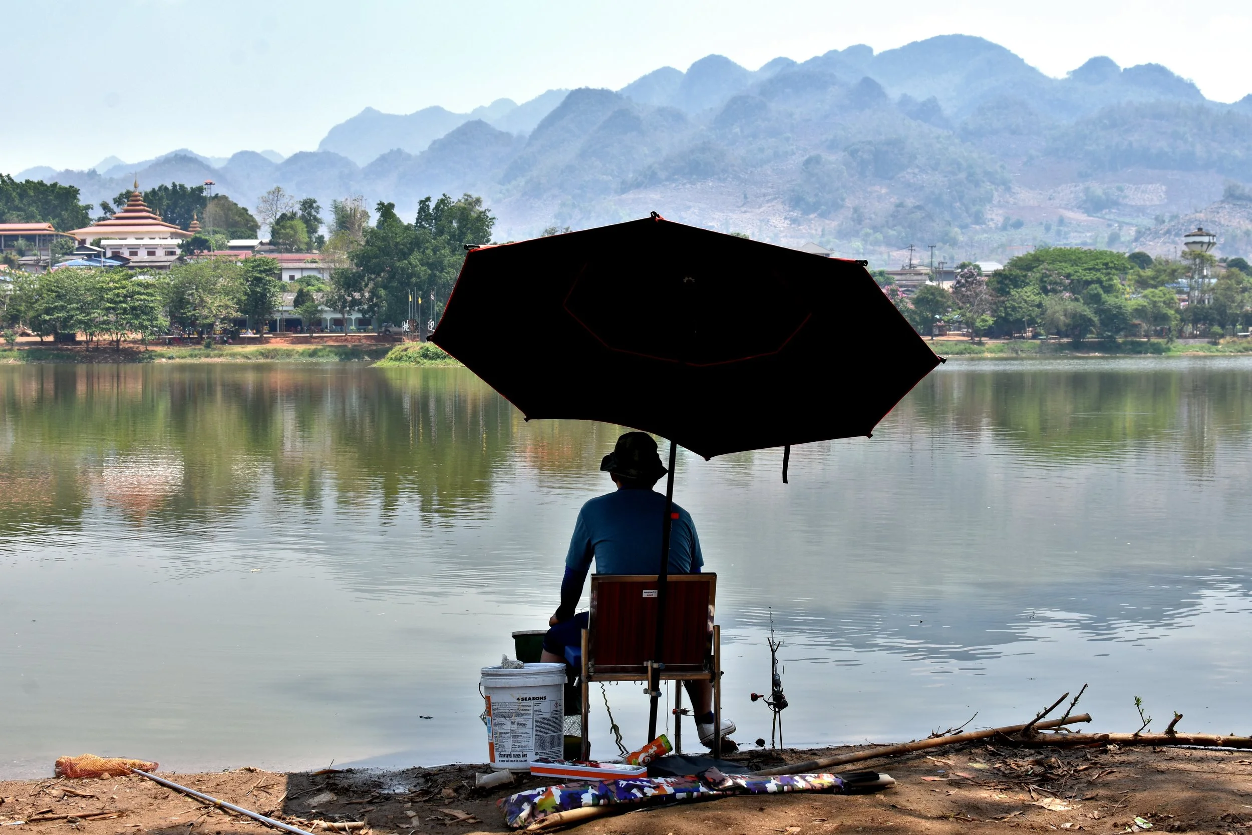 A man fishes in Arunothai, northern Thailand, a village established by Kuomintang (KMT) soldiers who fled China following the civil war. Myanmar is seen in the background. Al Jazeera, April 2024. 