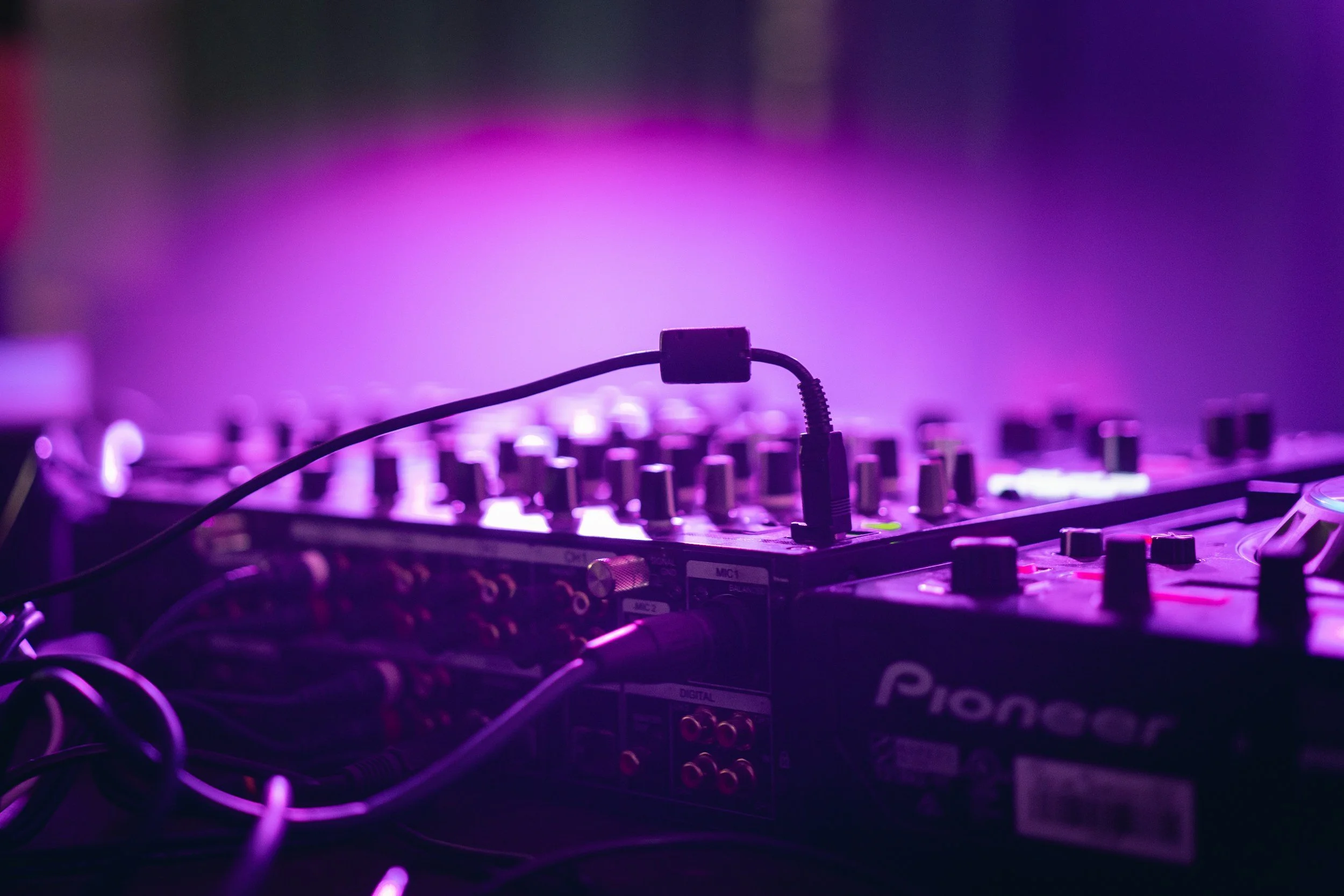 DJ-koneisto valaistuksessa, jossa violetin ja sinisen valon heijastuksia.