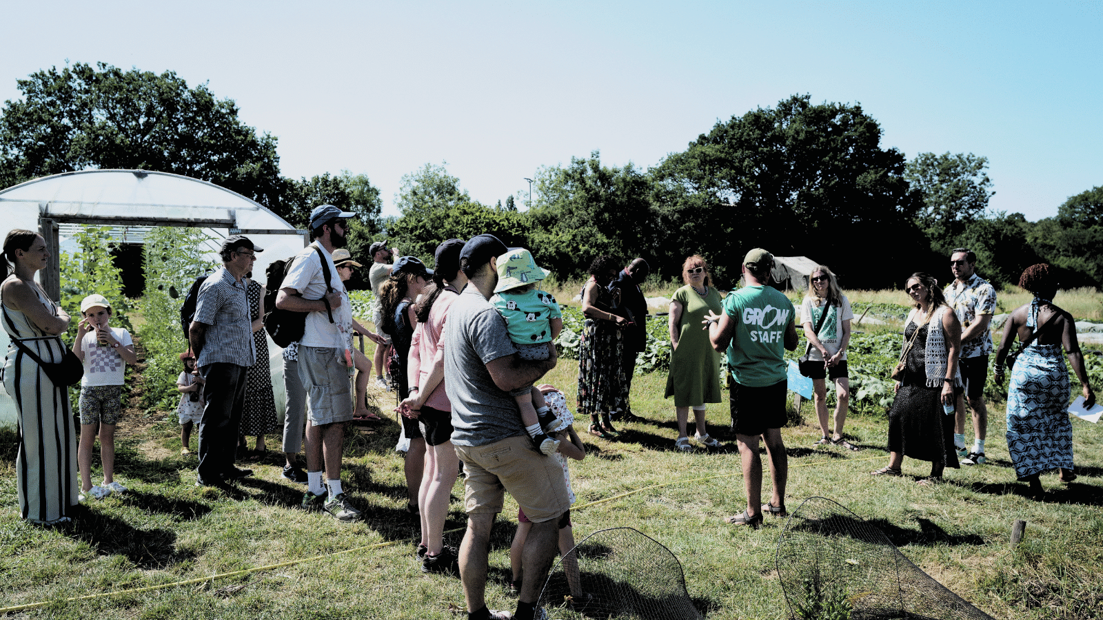 Group of people gathering together during a garden tour on a sunny day.