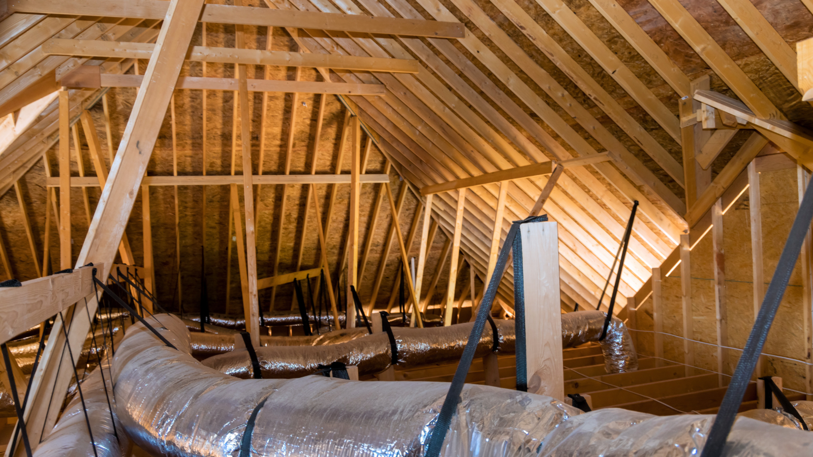 Construction inside an attic with wooden framing and exposed ductwork.